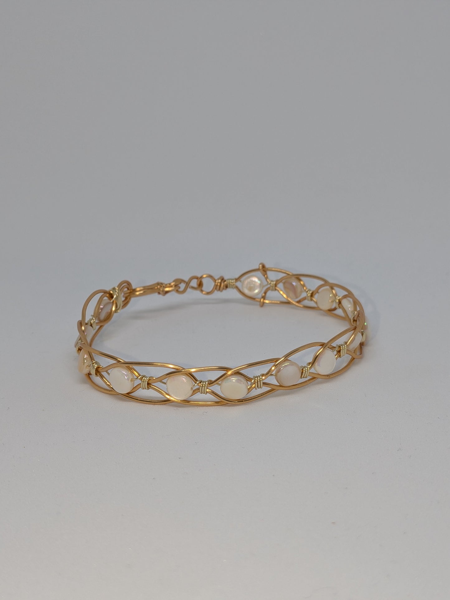 Geflochtenes goldfarbenes Armband mit weißen Muschelperlen