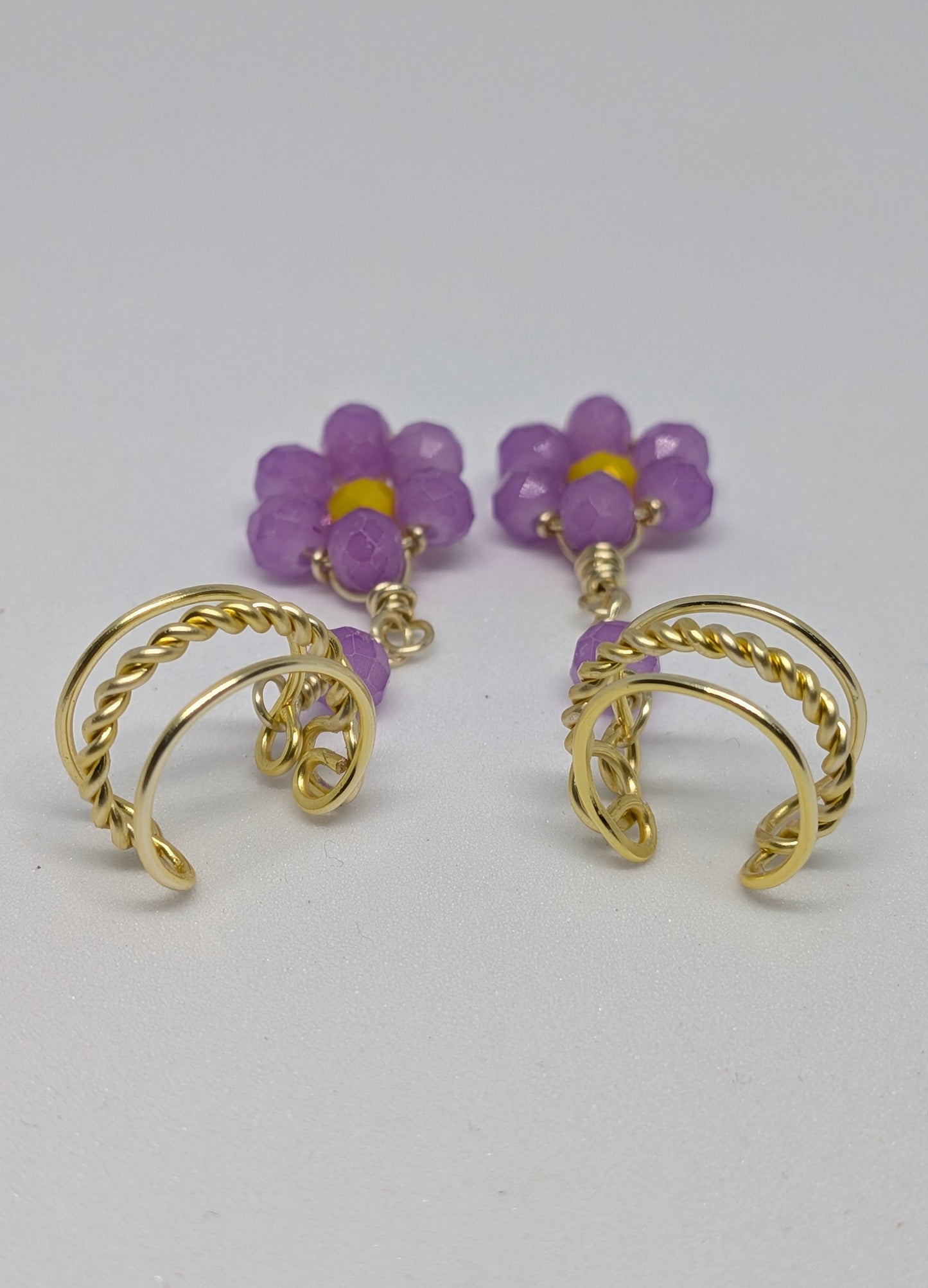 Ein Paar Earcuffs in Hellgold mit Blumenanhänger in sommerlich leuchtendem Flieder
