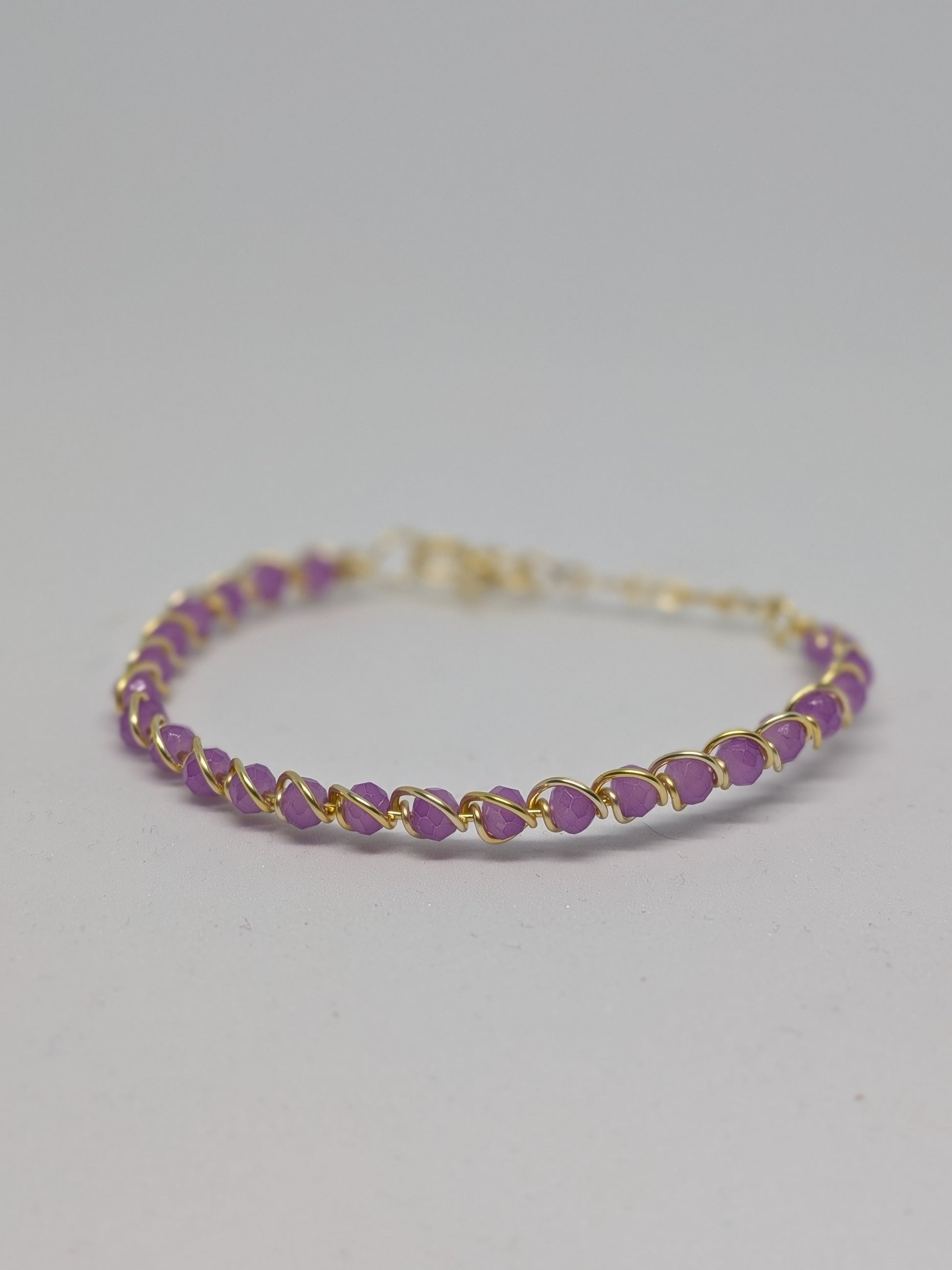 Elegantes, hellgoldfarbenes Armband mit geschliffenen fliederfarbenen Glasperlen. 