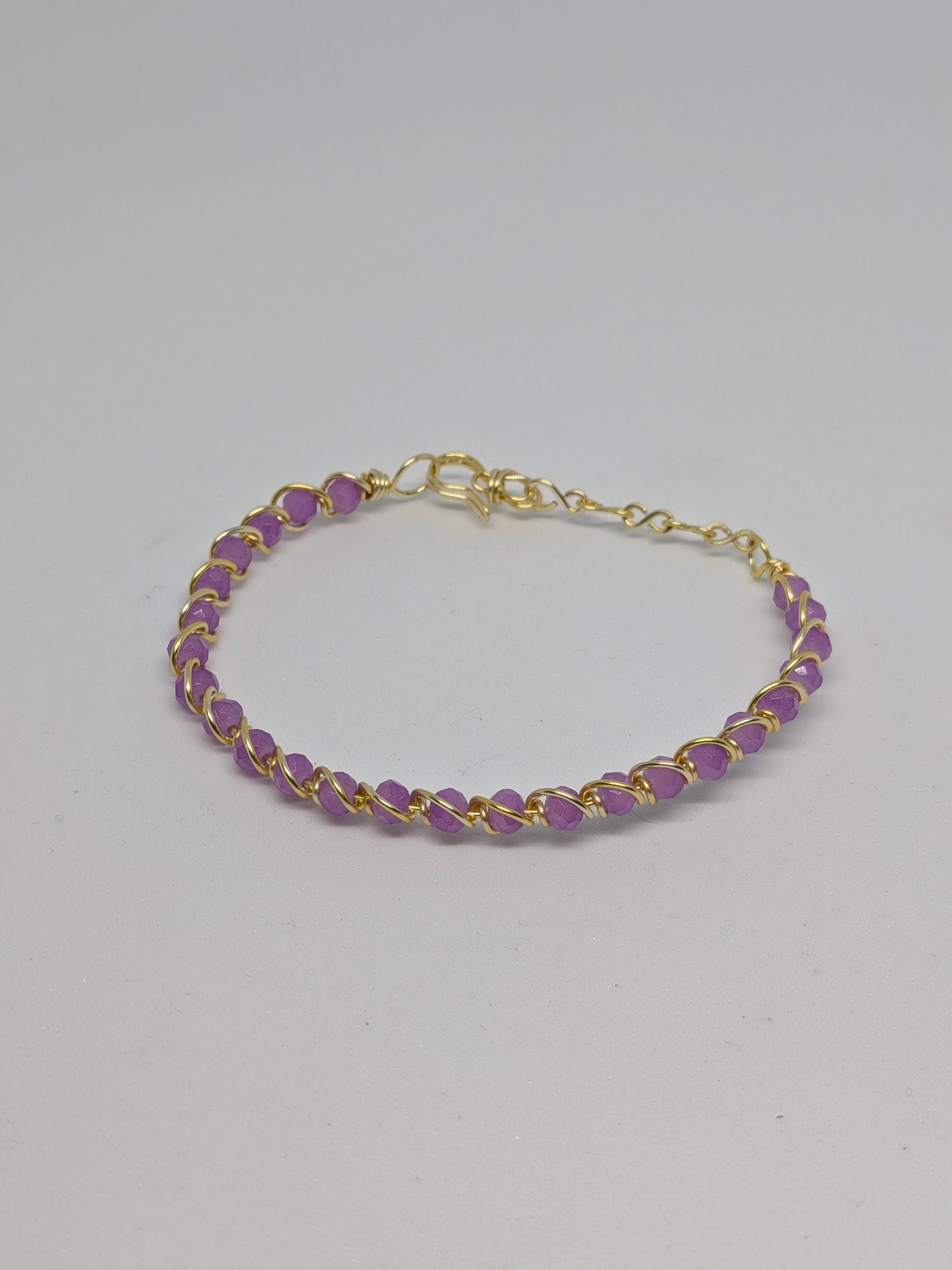 Elegantes, hellgoldfarbenes Armband mit geschliffenen fliederfarbenen Glasperlen. 