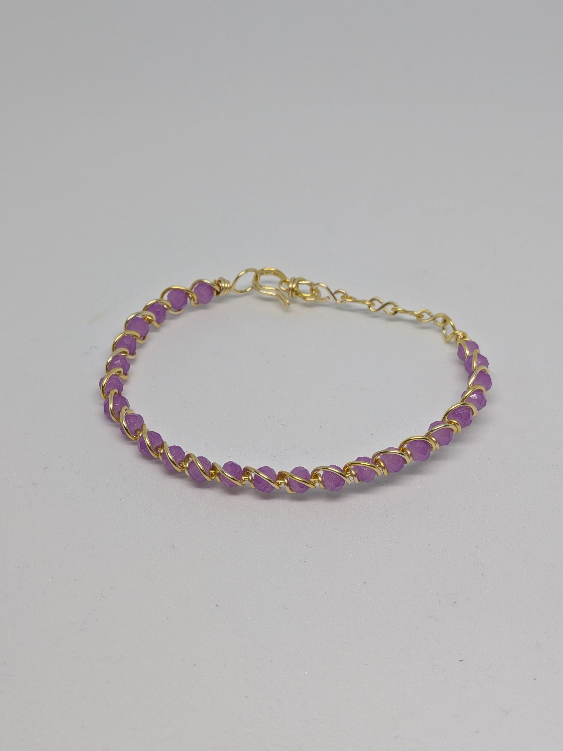Elegantes, hellgoldfarbenes Armband mit geschliffenen fliederfarbenen Glasperlen. 