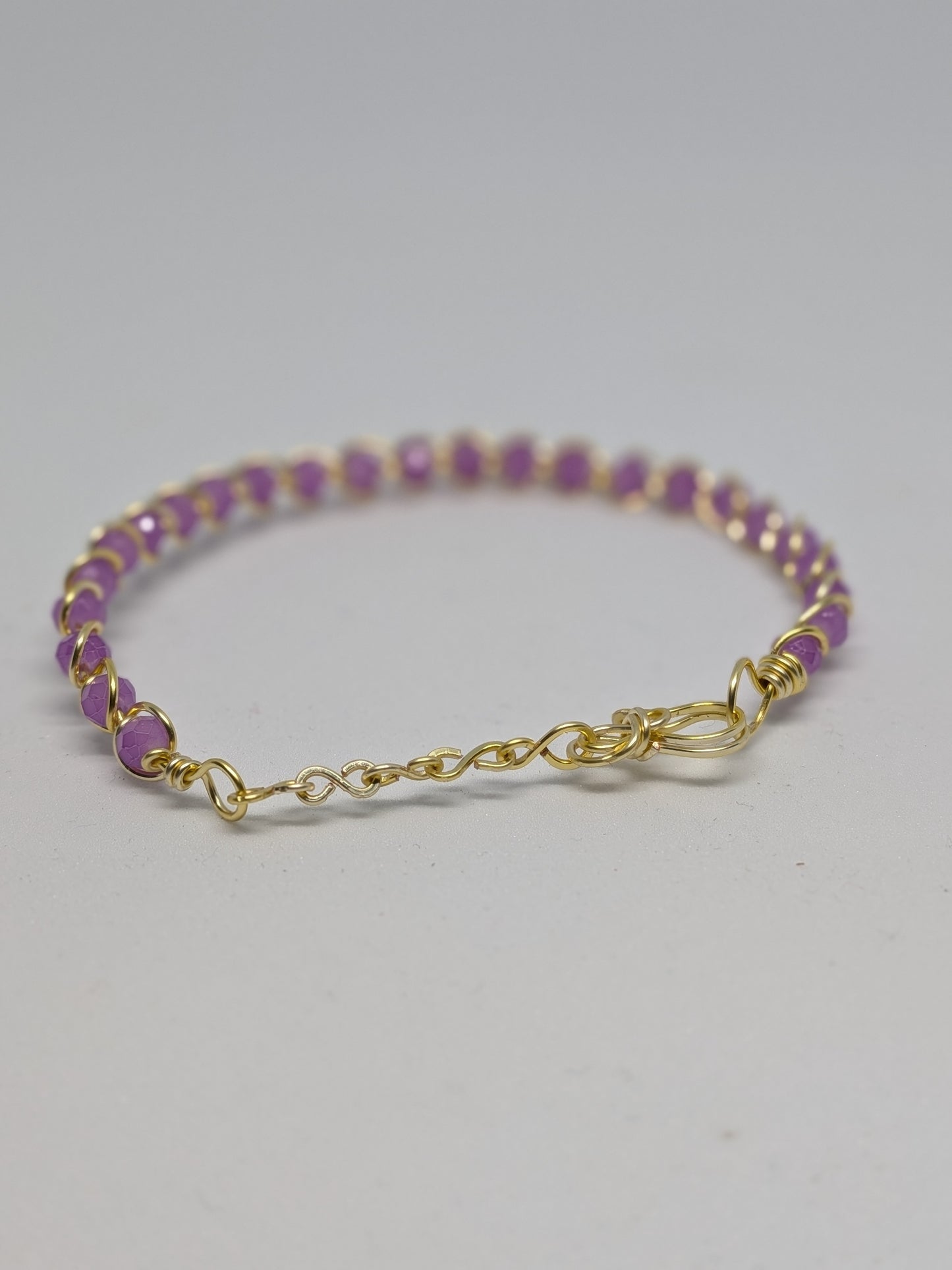 Elegantes, hellgoldfarbenes Armband mit geschliffenen fliederfarbenen Glasperlen. 