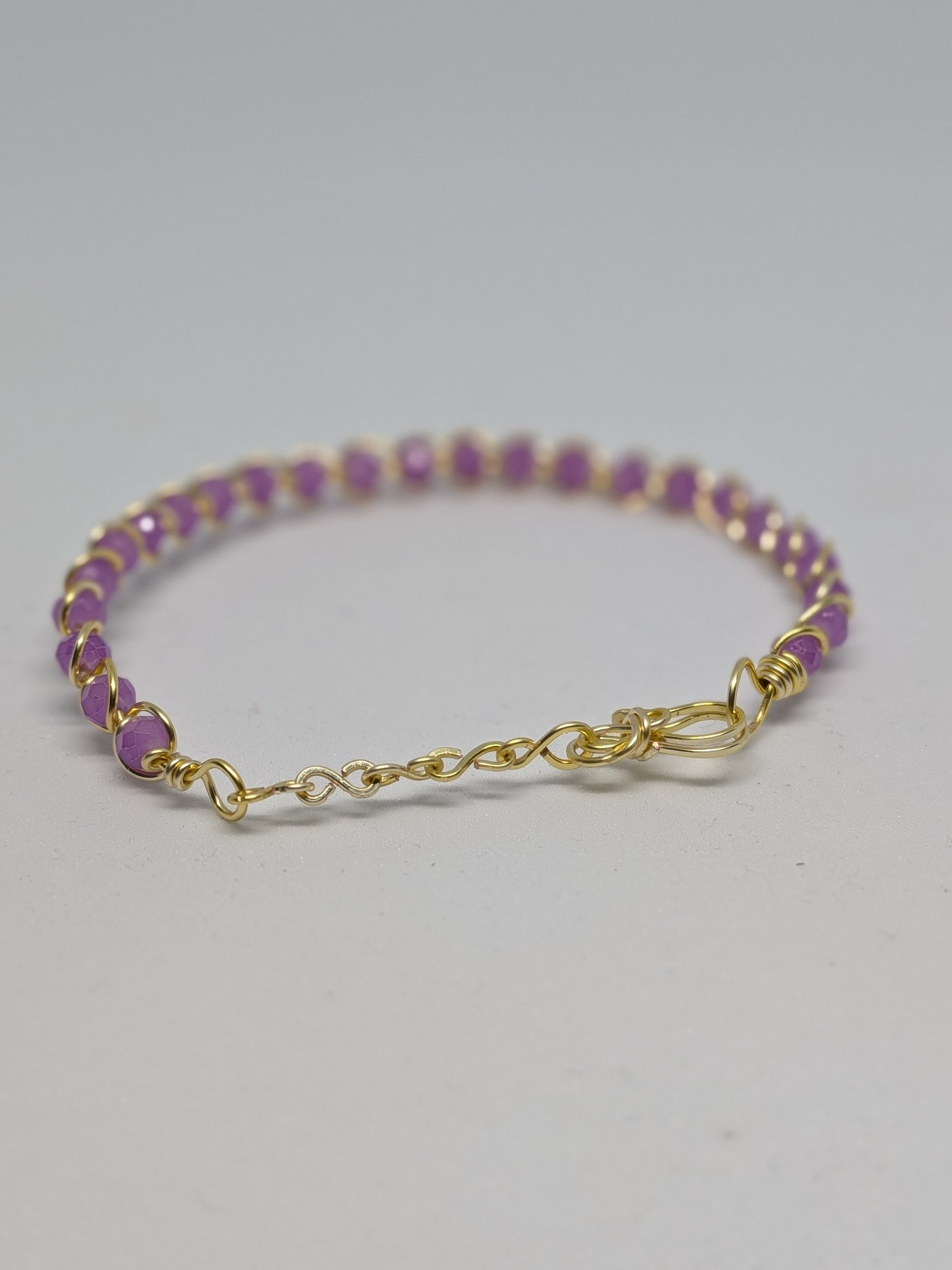 Elegantes, hellgoldfarbenes Armband mit geschliffenen fliederfarbenen Glasperlen. 