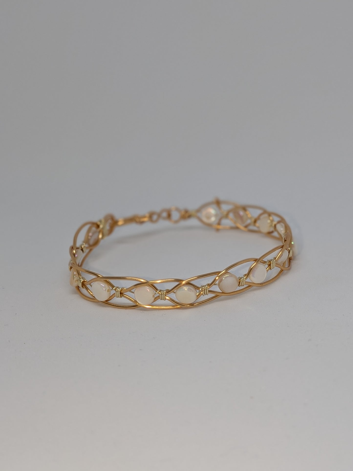 Geflochtenes goldfarbenes Armband mit weißen Muschelperlen