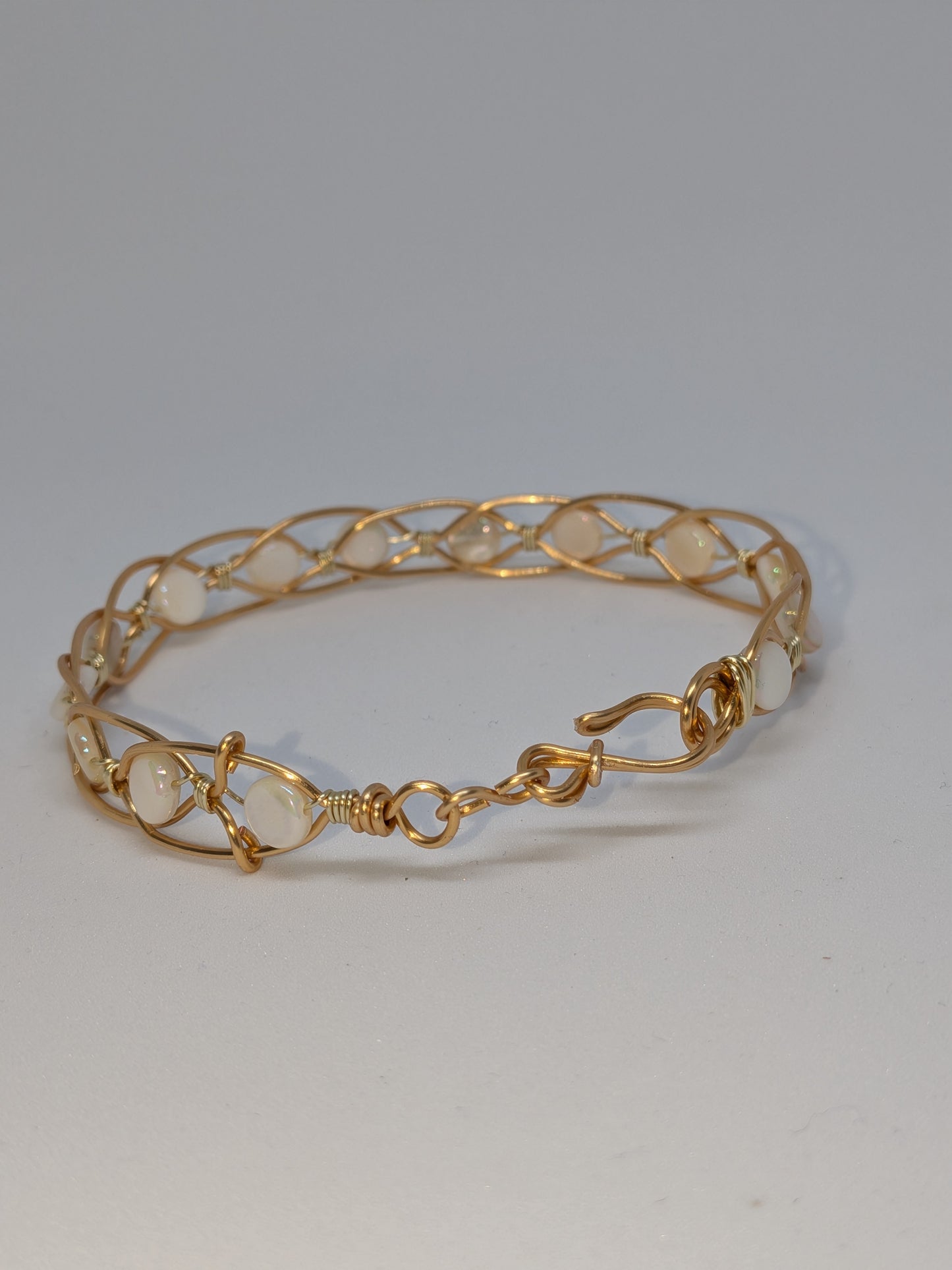 Geflochtenes goldfarbenes Armband mit weißen Muschelperlen