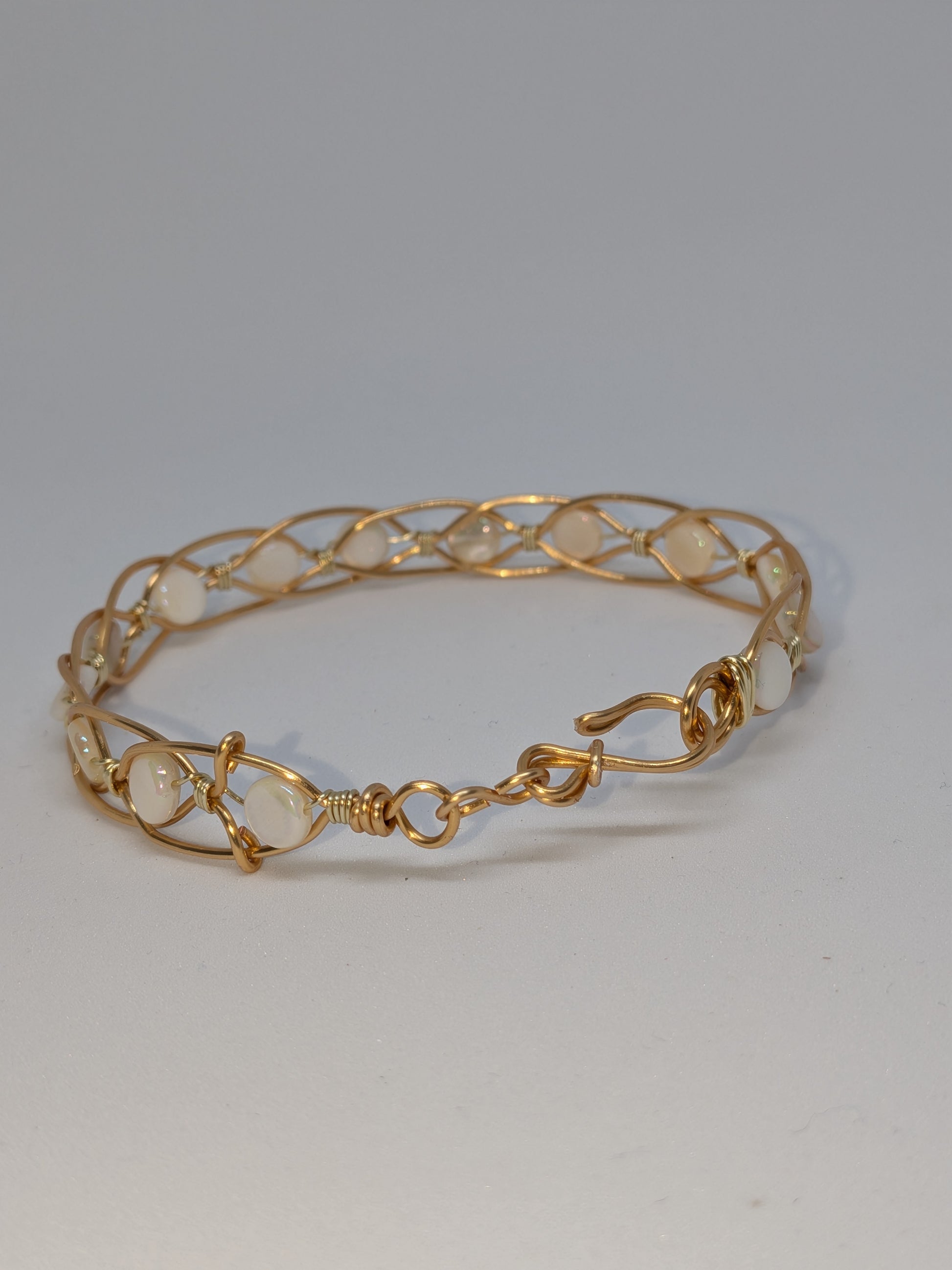 Geflochtenes goldfarbenes Armband mit weißen Muschelperlen