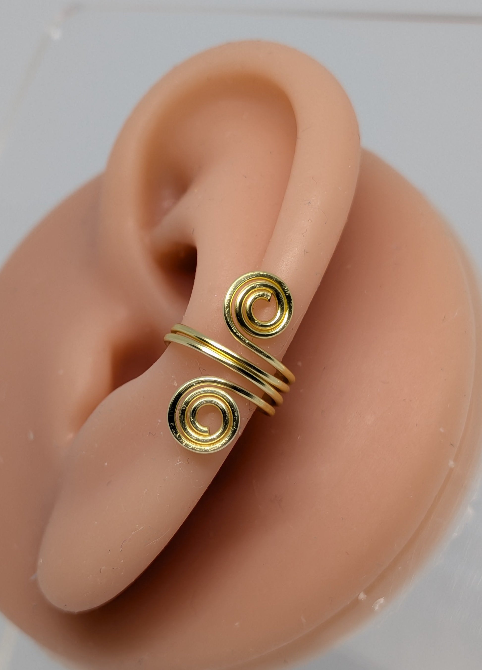 Einzelner Earcuff in Hellgold mit dekorativen Spiralen