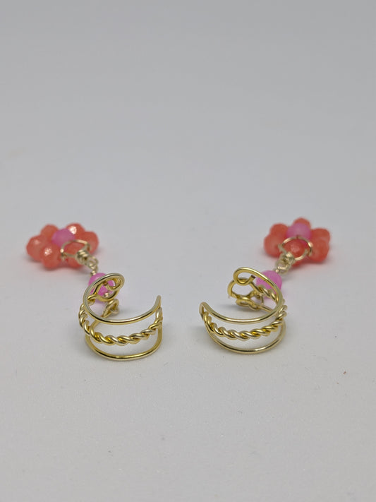 Ein Paar Earcuffs in Hellgold mit Blumenanhänger in sommerlich leuchtendem Orange 