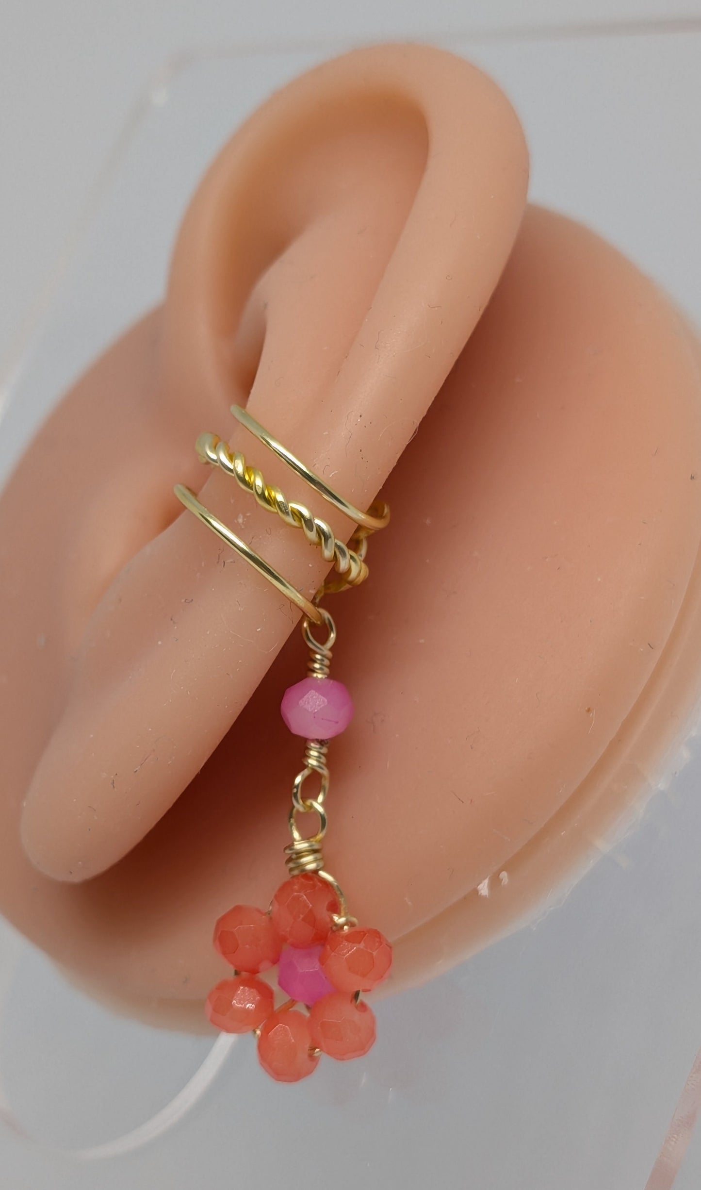 Ein Paar Earcuffs in Hellgold mit Blumenanhänger in sommerlich leuchtendem Orange 