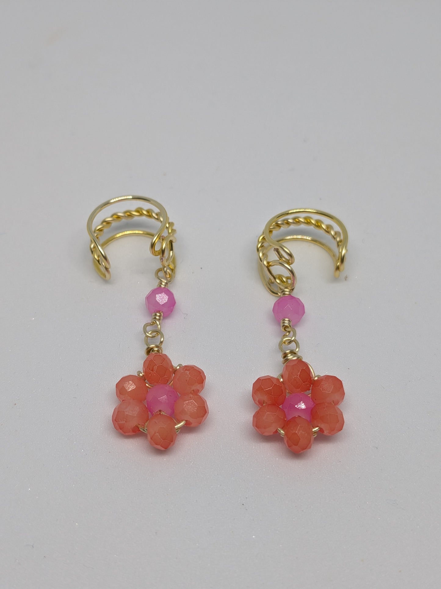 Ein Paar Earcuffs in Hellgold mit Blumenanhänger in sommerlich leuchtendem Orange 