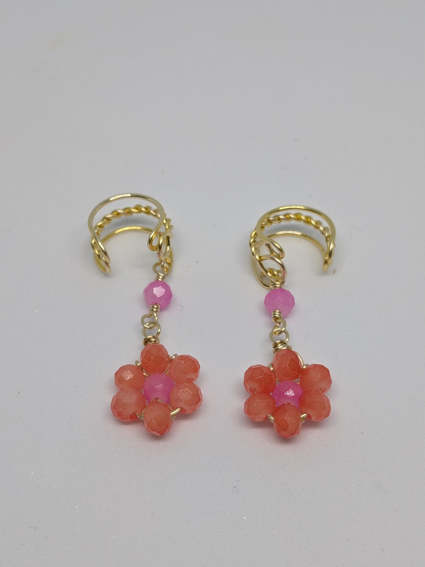 Ein Paar Earcuffs in Hellgold mit Blumenanhänger in sommerlich leuchtendem Orange 