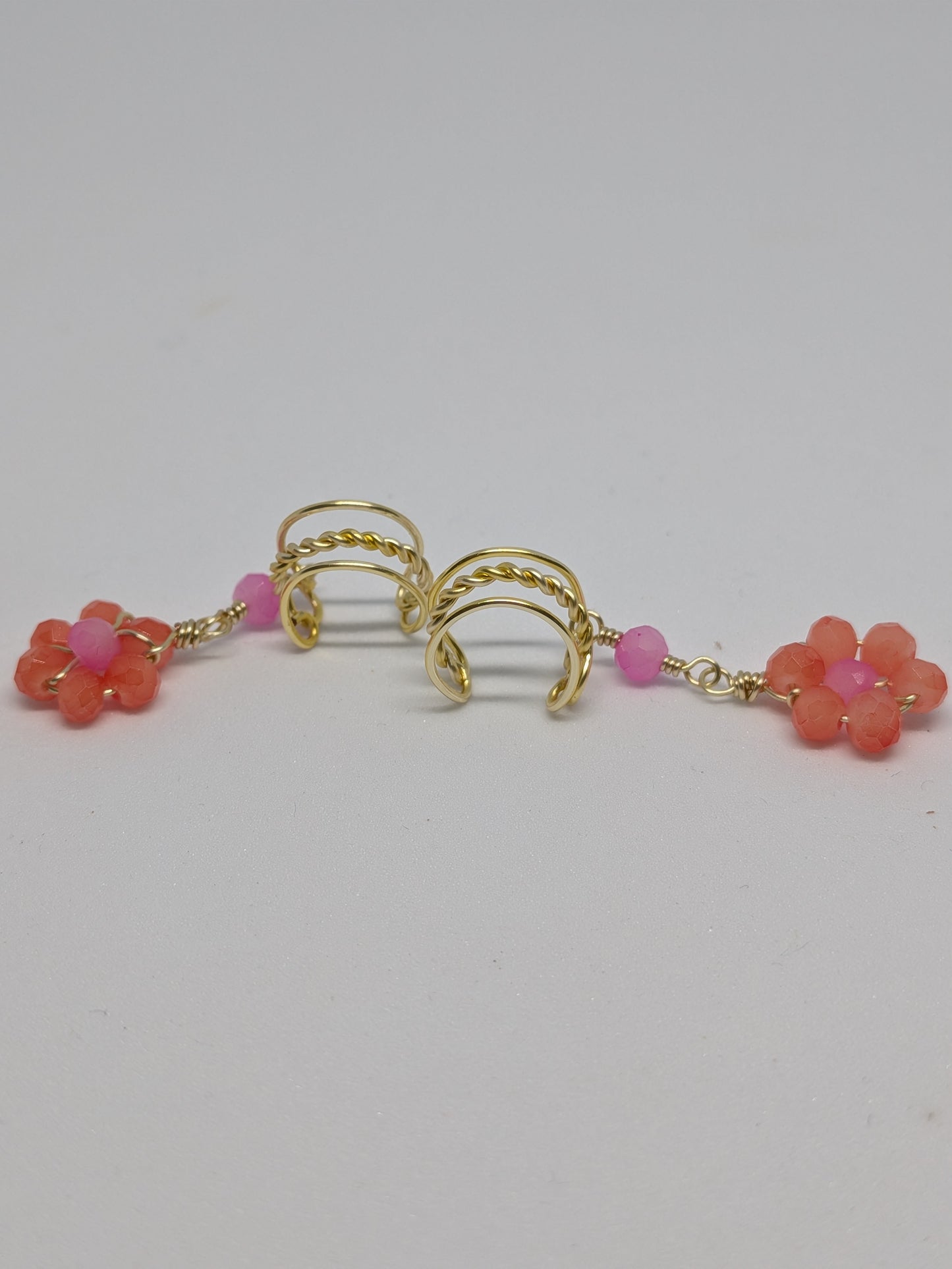 Ein Paar Earcuffs in Hellgold mit Blumenanhänger in sommerlich leuchtendem Orange 
