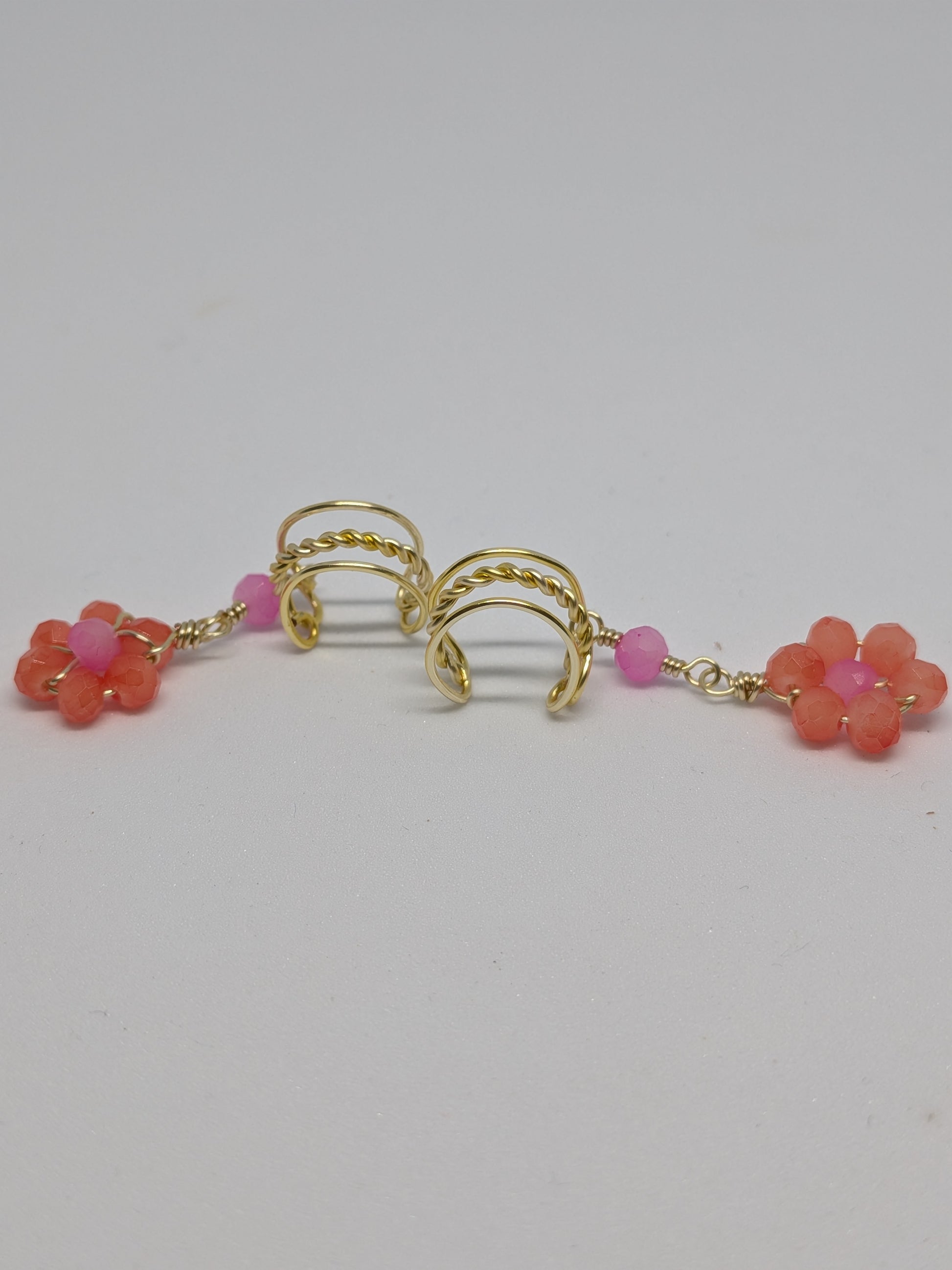 Ein Paar Earcuffs in Hellgold mit Blumenanhänger in sommerlich leuchtendem Orange 