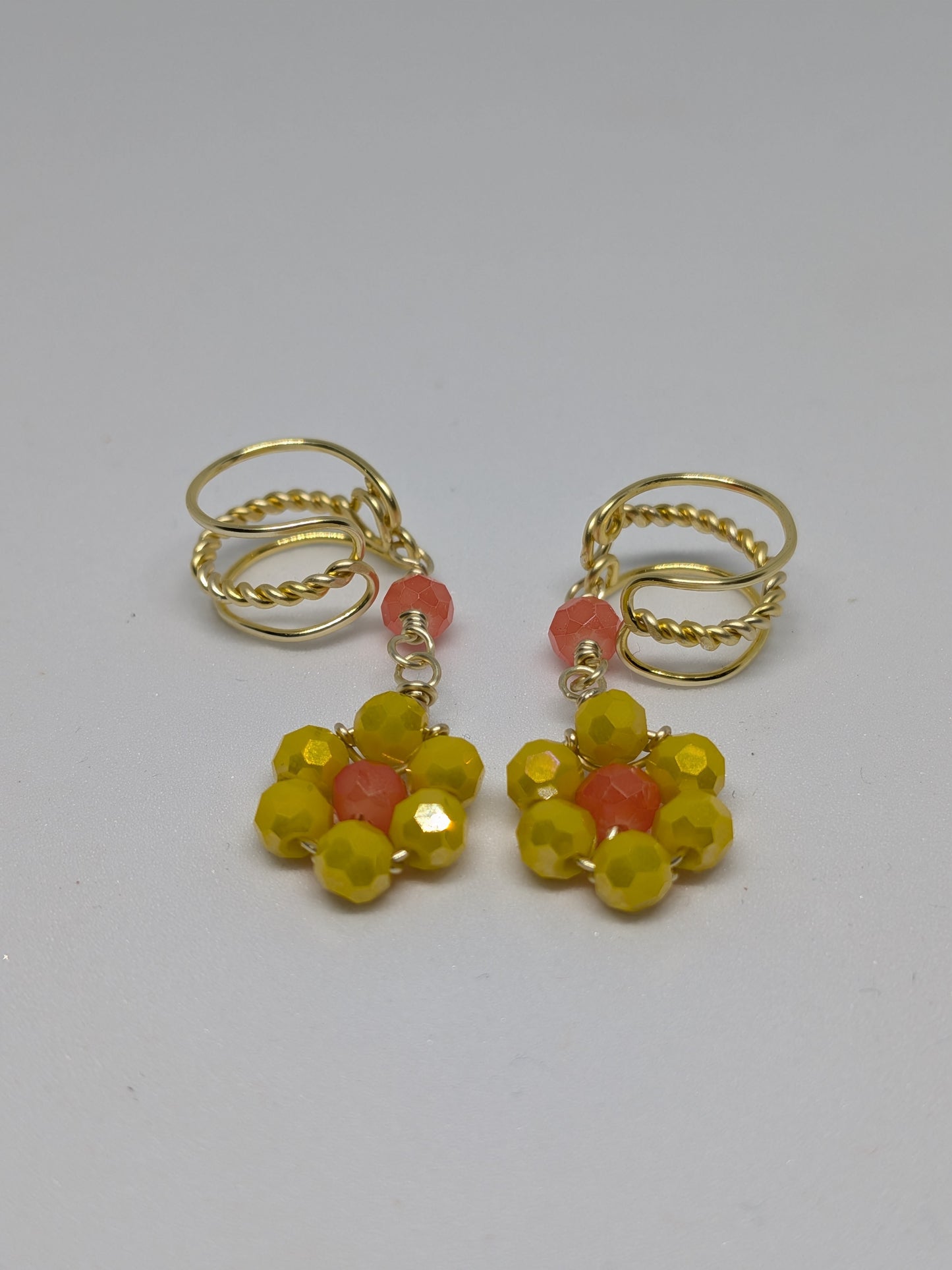 Ein Paar Earcuffs in Hellgold mit Blumenanhänger in sommerlich leuchtendem Gelb 