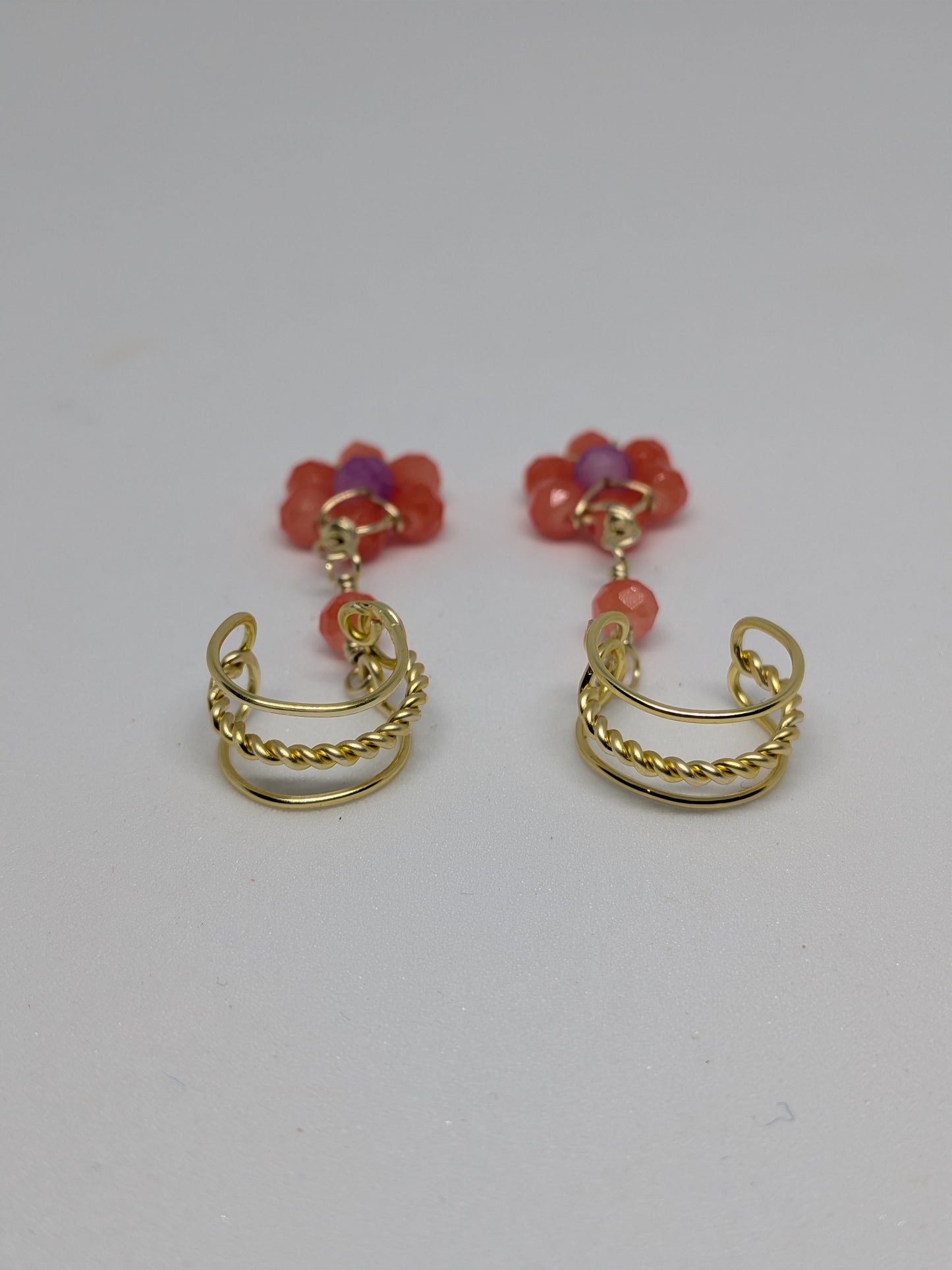 Ein Paar Earcuffs in Hellgold mit Blumenanhänger in sommerlich leuchtendem Orange