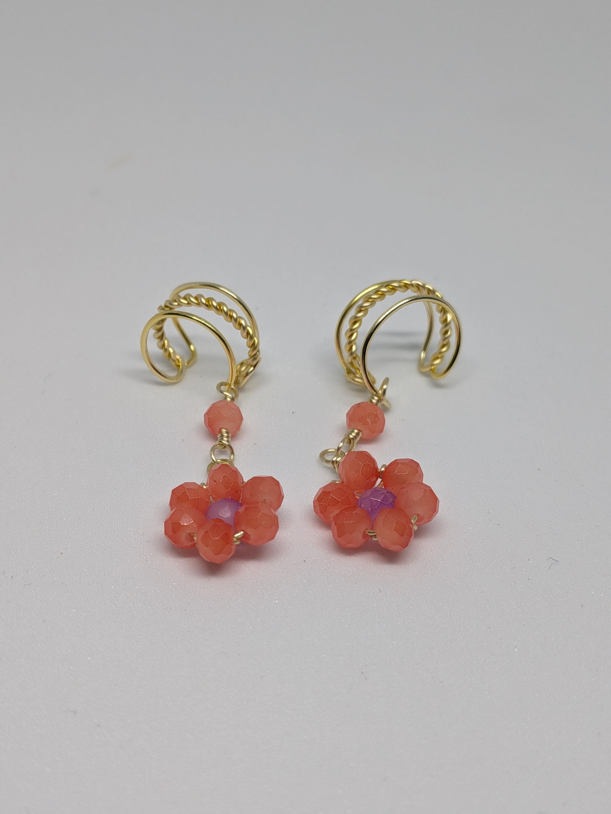 Ein Paar Earcuffs in Hellgold mit Blumenanhänger in sommerlich leuchtendem Orange
