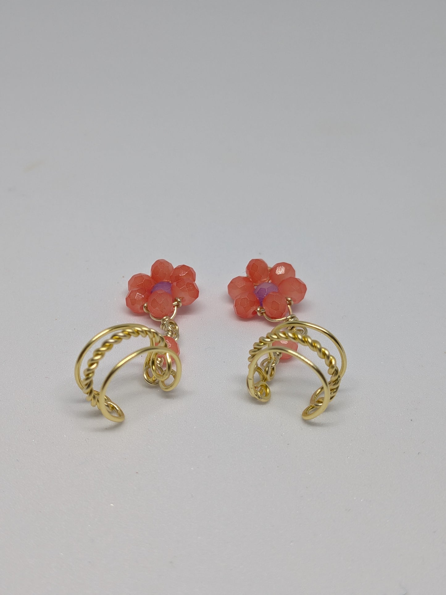 Ein Paar Earcuffs in Hellgold mit Blumenanhänger in sommerlich leuchtendem Orange