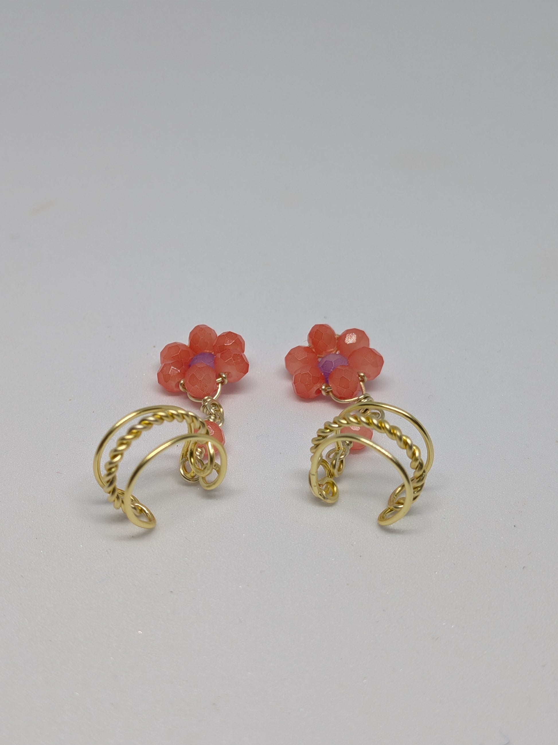Ein Paar Earcuffs in Hellgold mit Blumenanhänger in sommerlich leuchtendem Orange