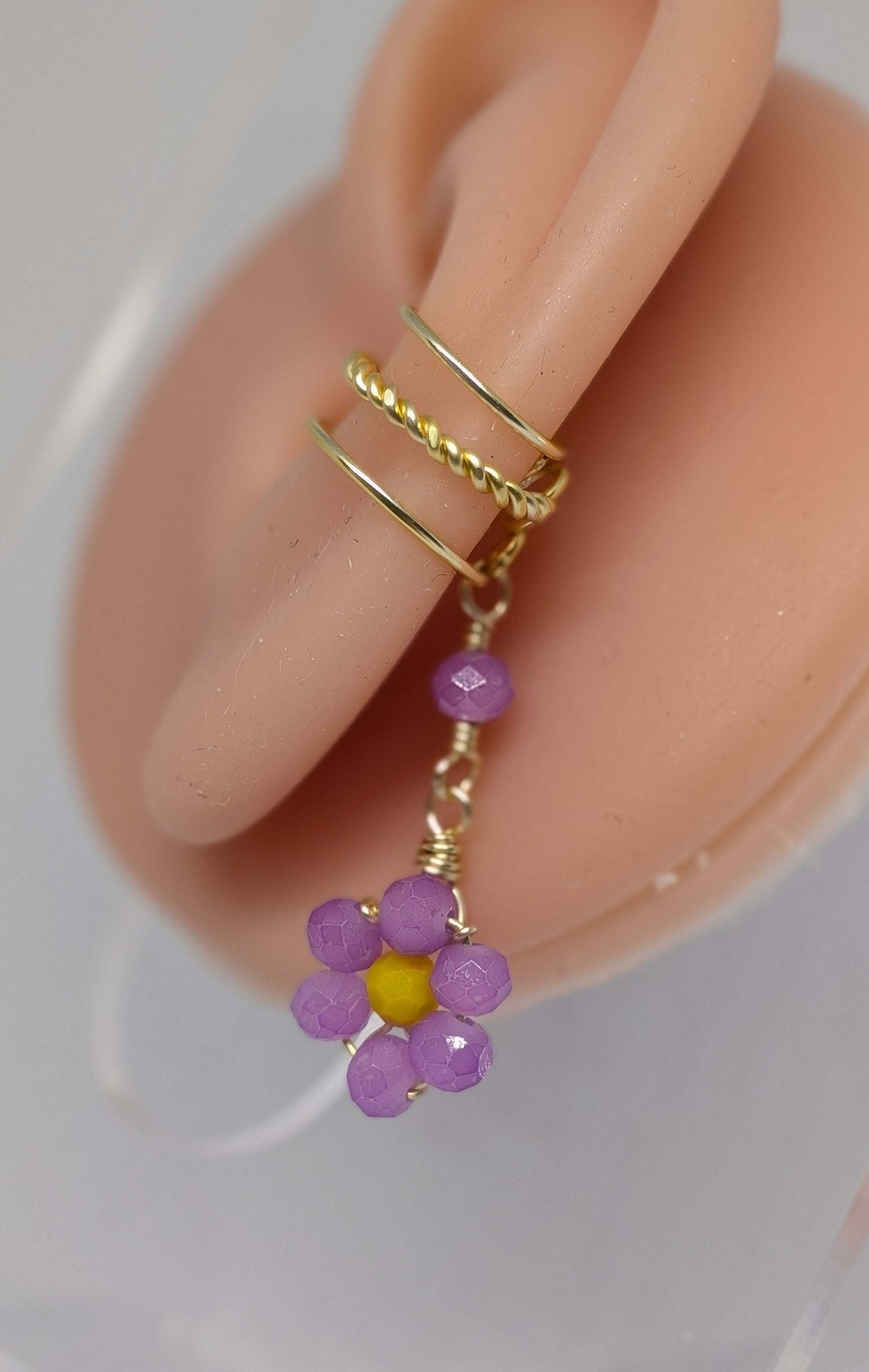 Ein Paar Earcuffs in Hellgold mit Blumenanhänger in sommerlich leuchtendem Flieder