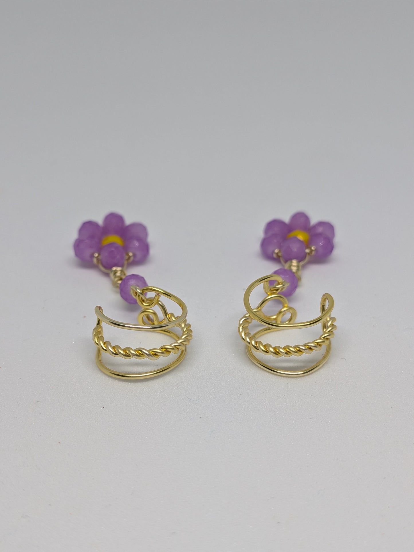 Ein Paar Earcuffs in Hellgold mit Blumenanhänger in sommerlich leuchtendem Flieder