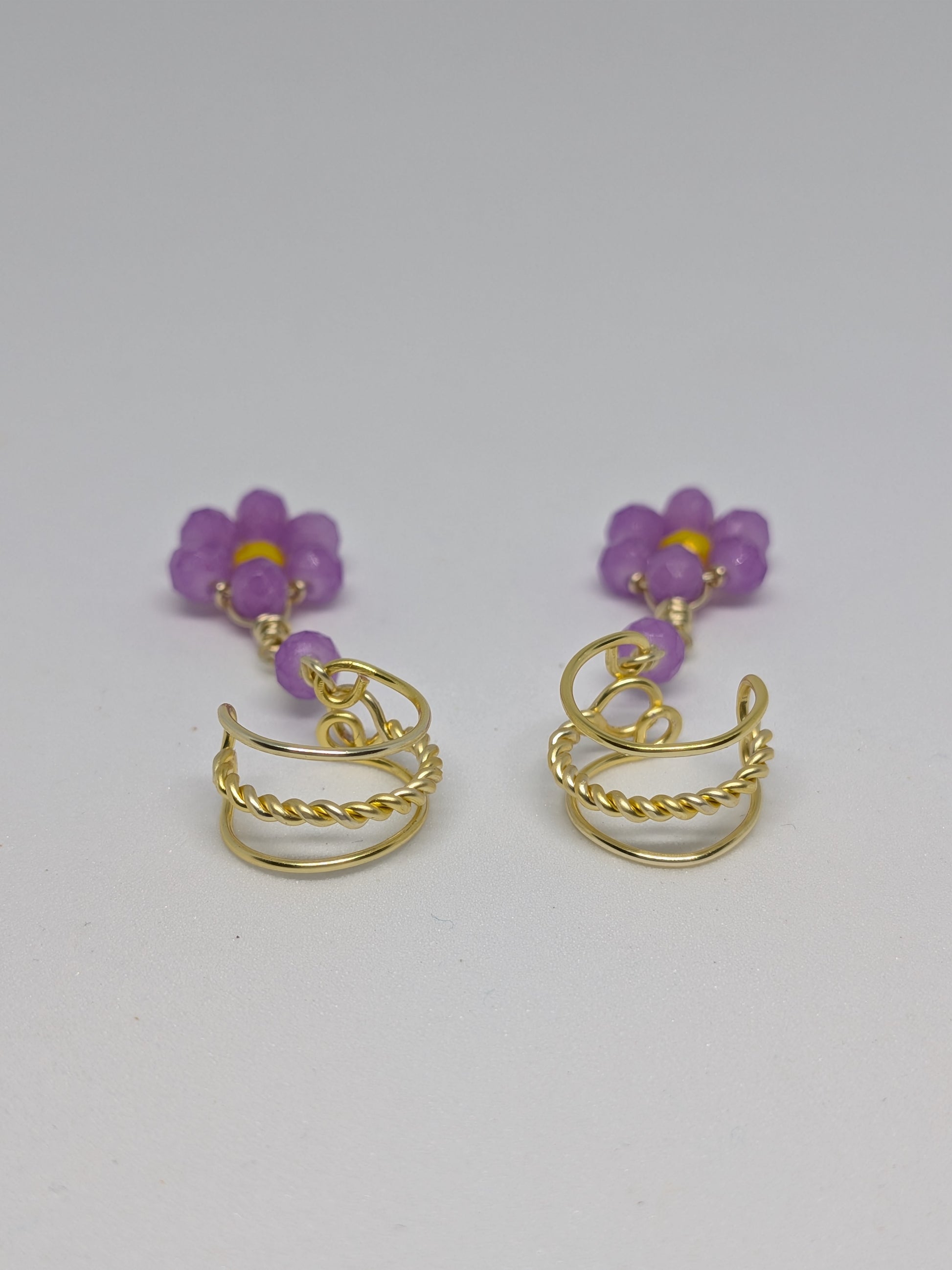 Ein Paar Earcuffs in Hellgold mit Blumenanhänger in sommerlich leuchtendem Flieder