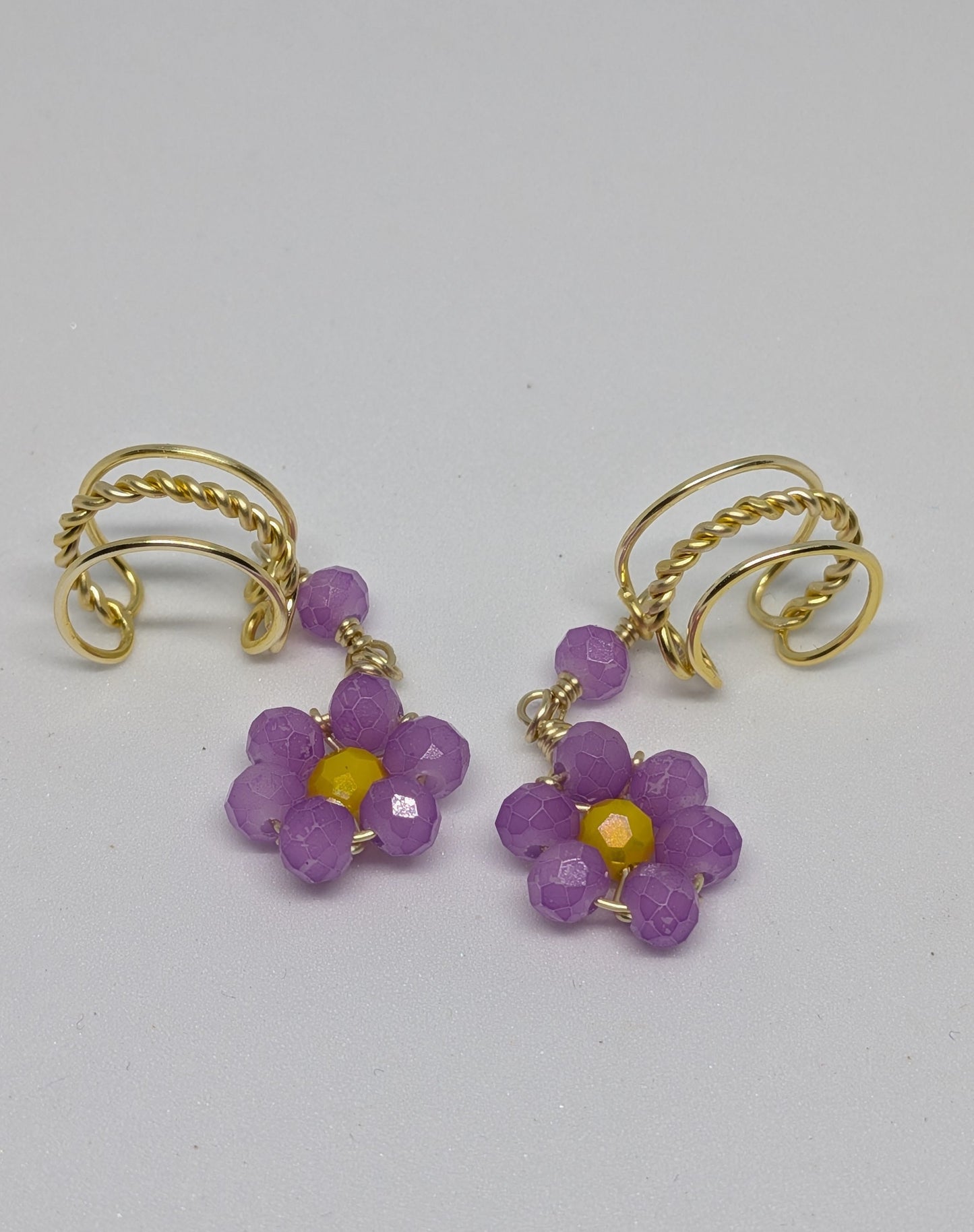 Ein Paar Earcuffs in Hellgold mit Blumenanhänger in sommerlich leuchtendem Flieder