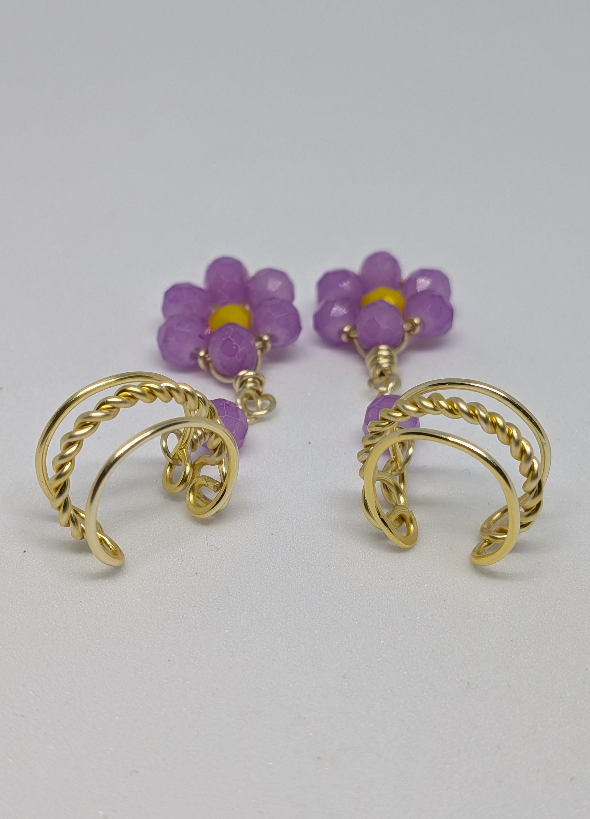 Ein Paar Earcuffs in Hellgold mit Blumenanhänger in sommerlich leuchtendem Flieder