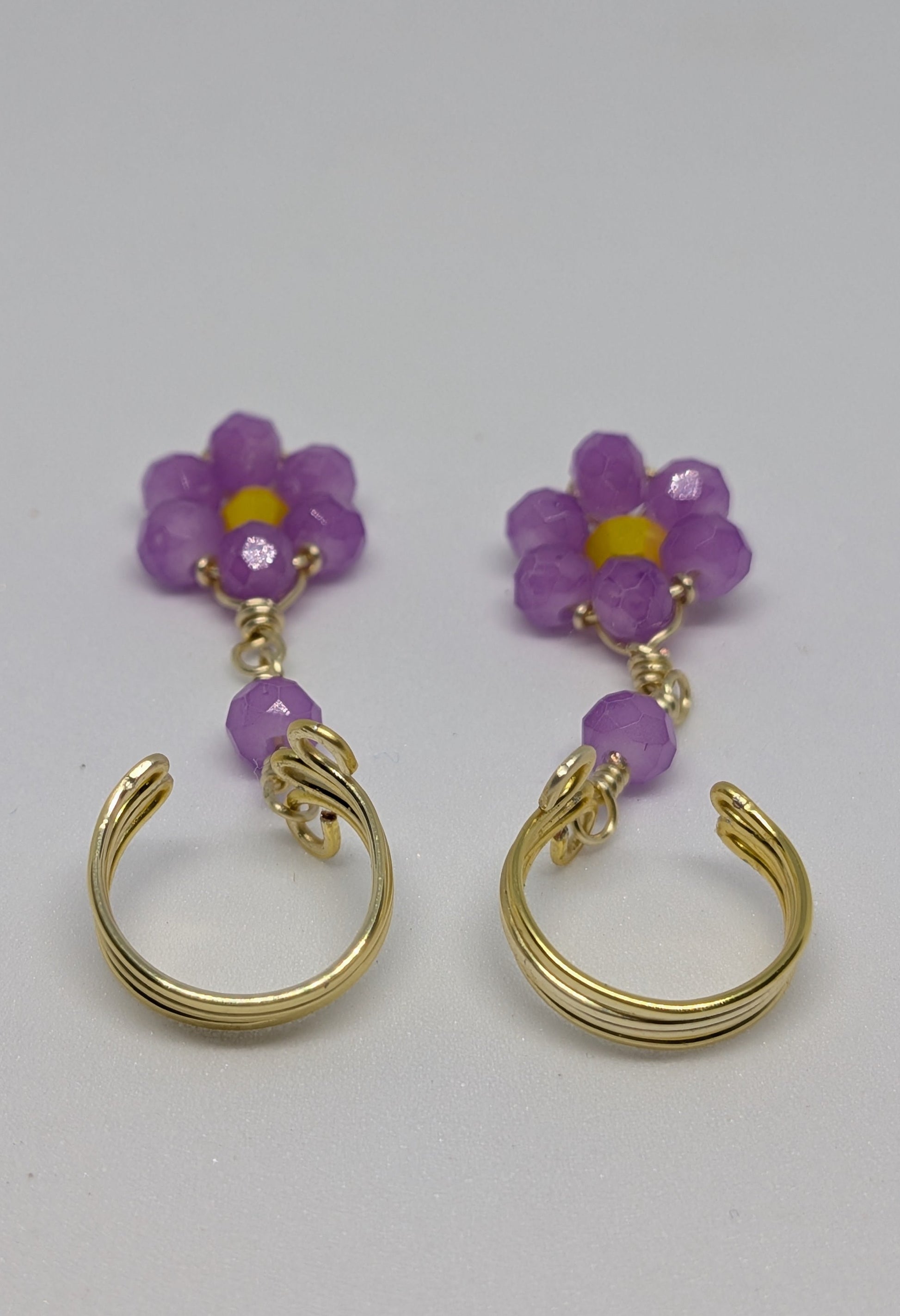 Ein Paar Earcuffs in Hellgold mit Blumenanhänger in sommerlich leuchtendem Flieder