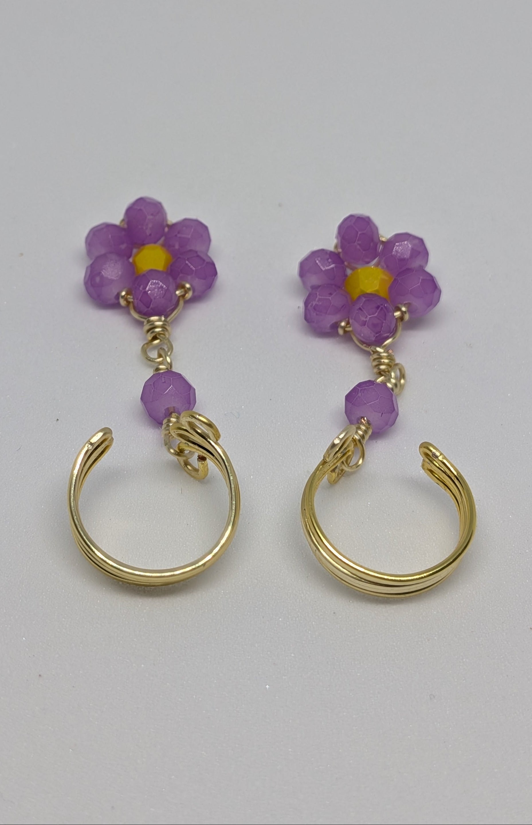 Ein Paar Earcuffs in Hellgold mit Blumenanhänger in sommerlich leuchtendem Flieder