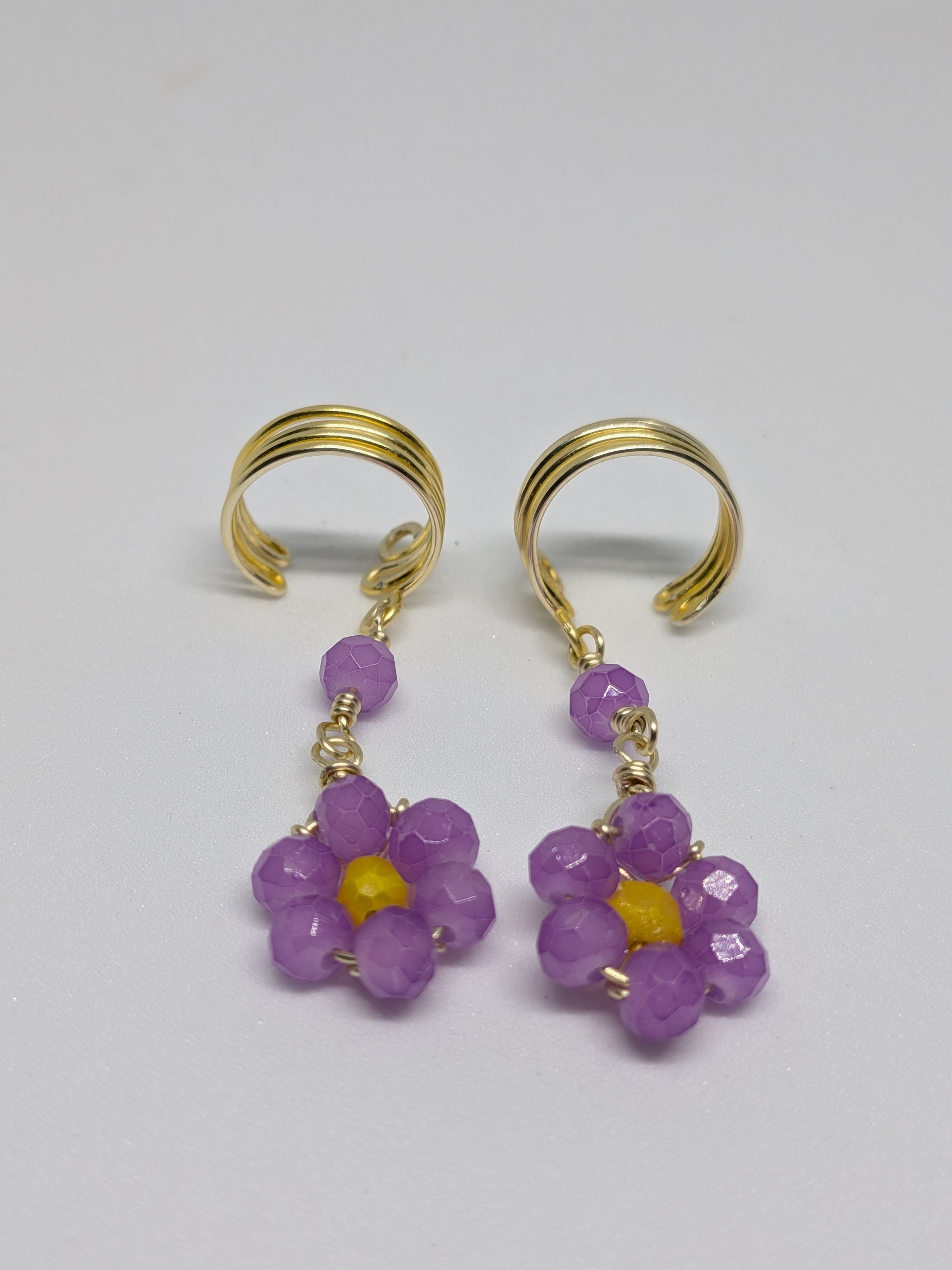 Ein Paar Earcuffs in Hellgold mit Blumenanhänger in sommerlich leuchtendem Flieder