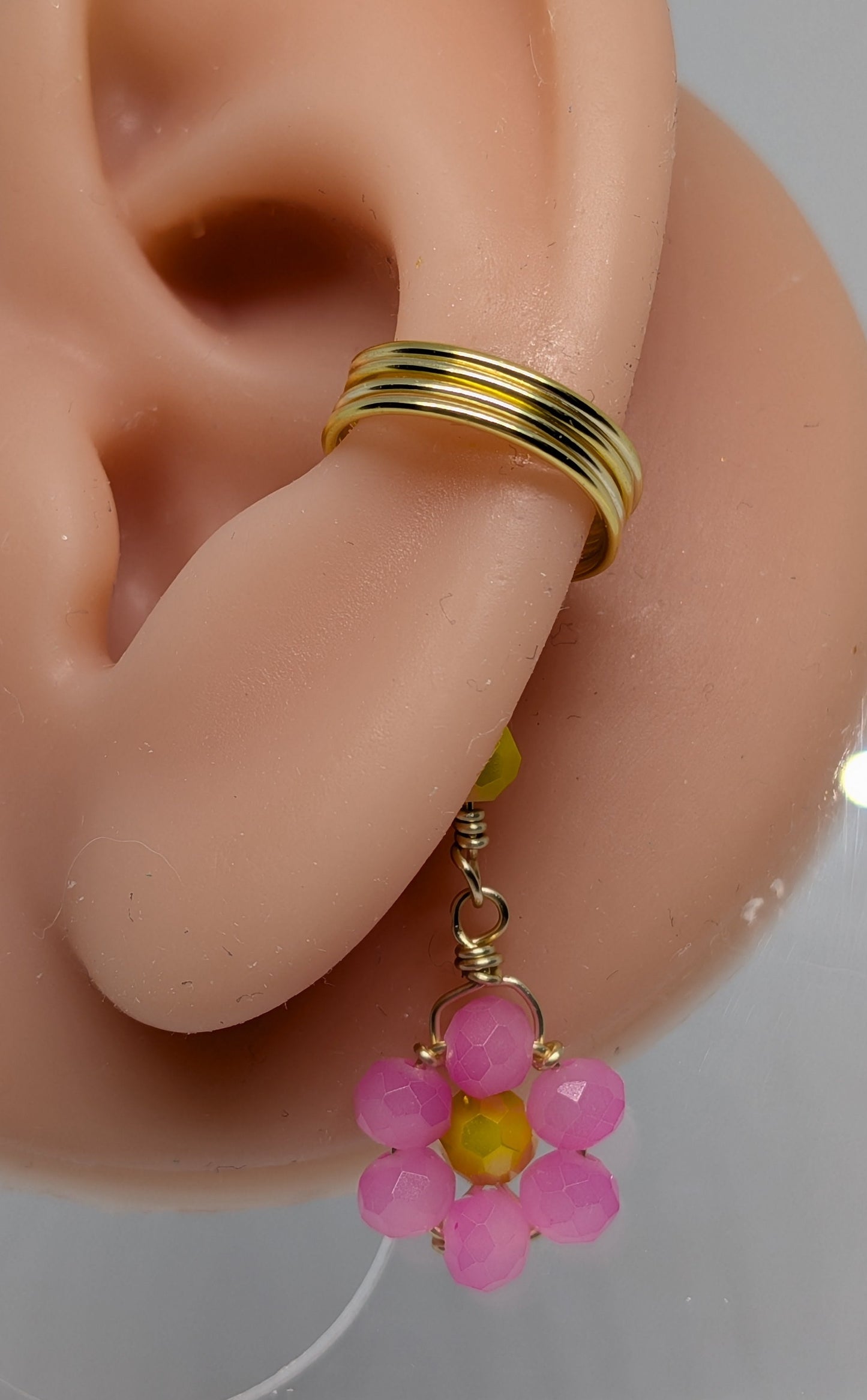 Ein Paar Earcuffs in Hellgold mit Blumenanhänger in sommerlich leuchtendem Pink
