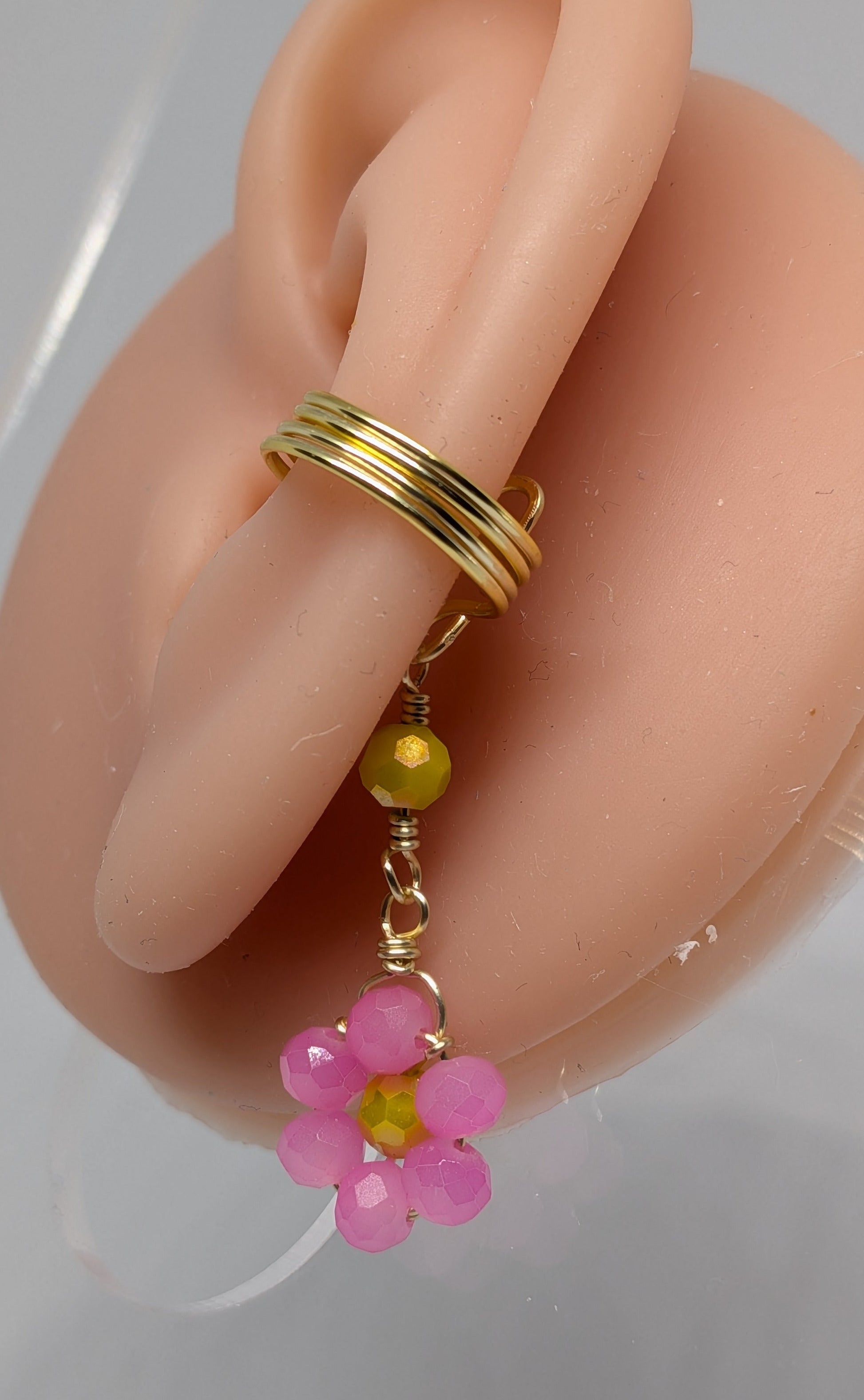 Ein Paar Earcuffs in Hellgold mit Blumenanhänger in sommerlich leuchtendem Pink