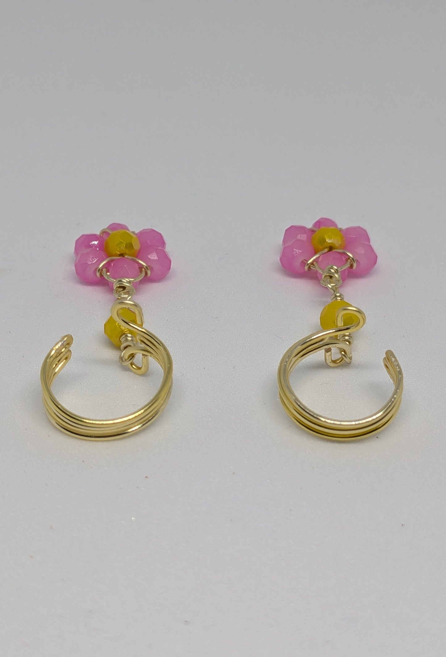 Ein Paar Earcuffs in Hellgold mit Blumenanhänger in sommerlich leuchtendem Pink