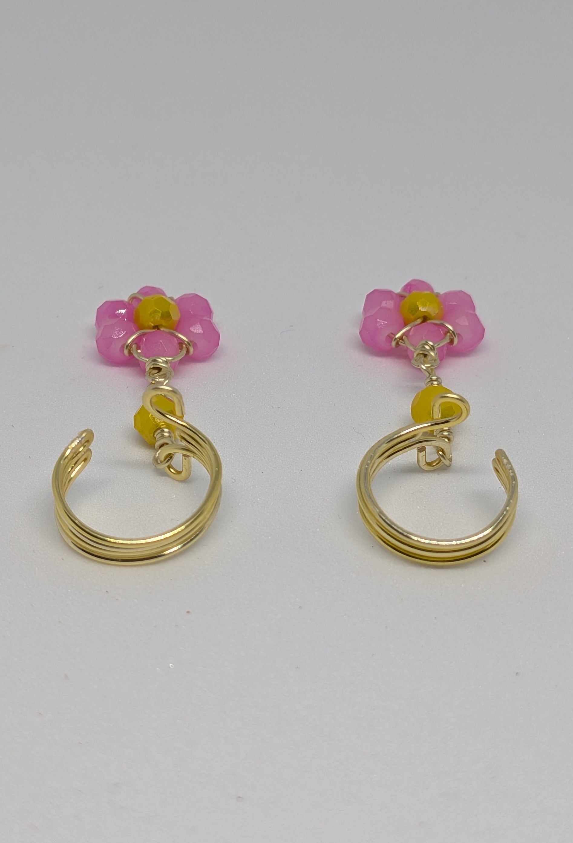 Ein Paar Earcuffs in Hellgold mit Blumenanhänger in sommerlich leuchtendem Pink