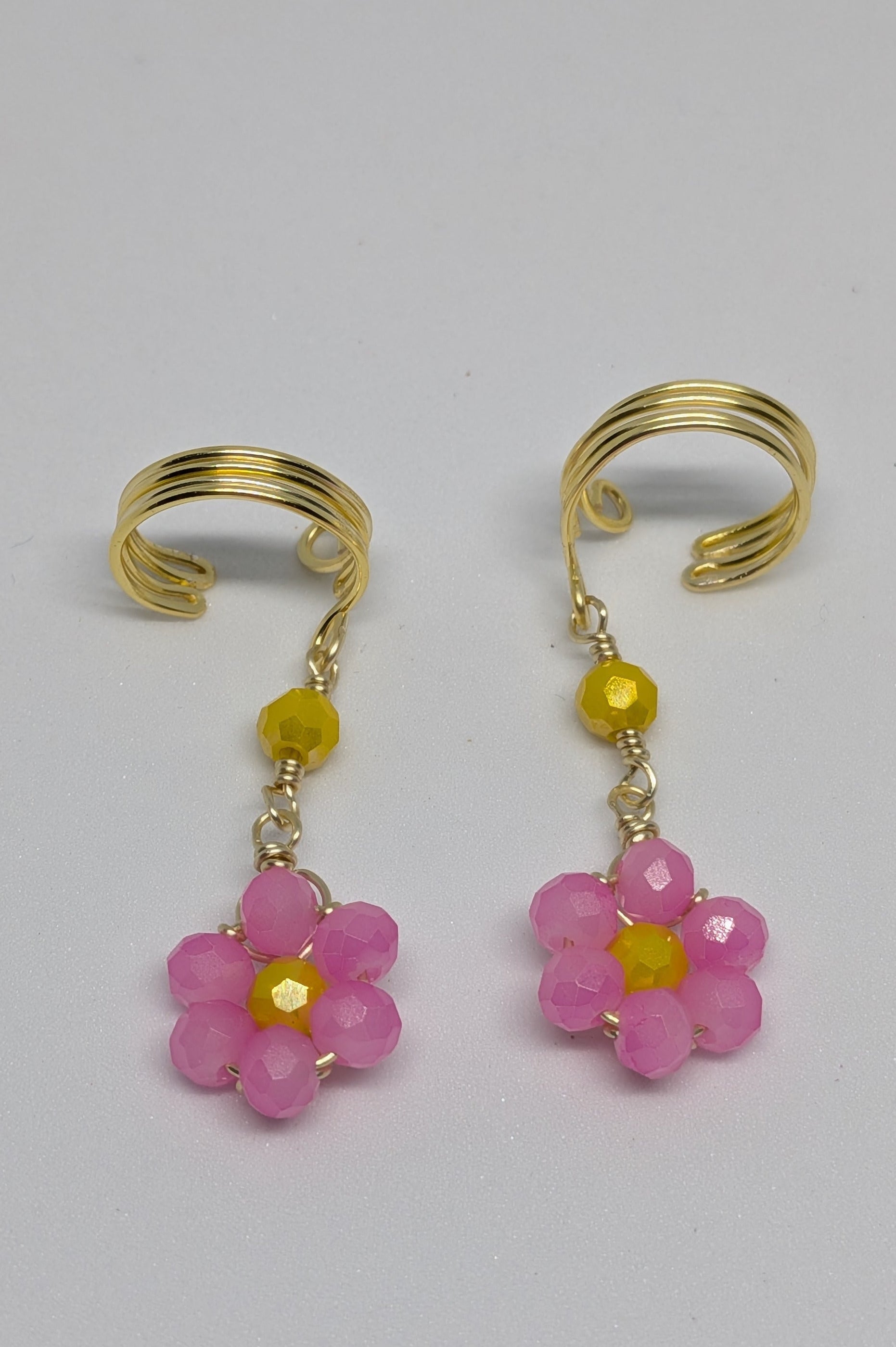 Ein Paar Earcuffs in Hellgold mit Blumenanhänger in sommerlich leuchtendem Pink