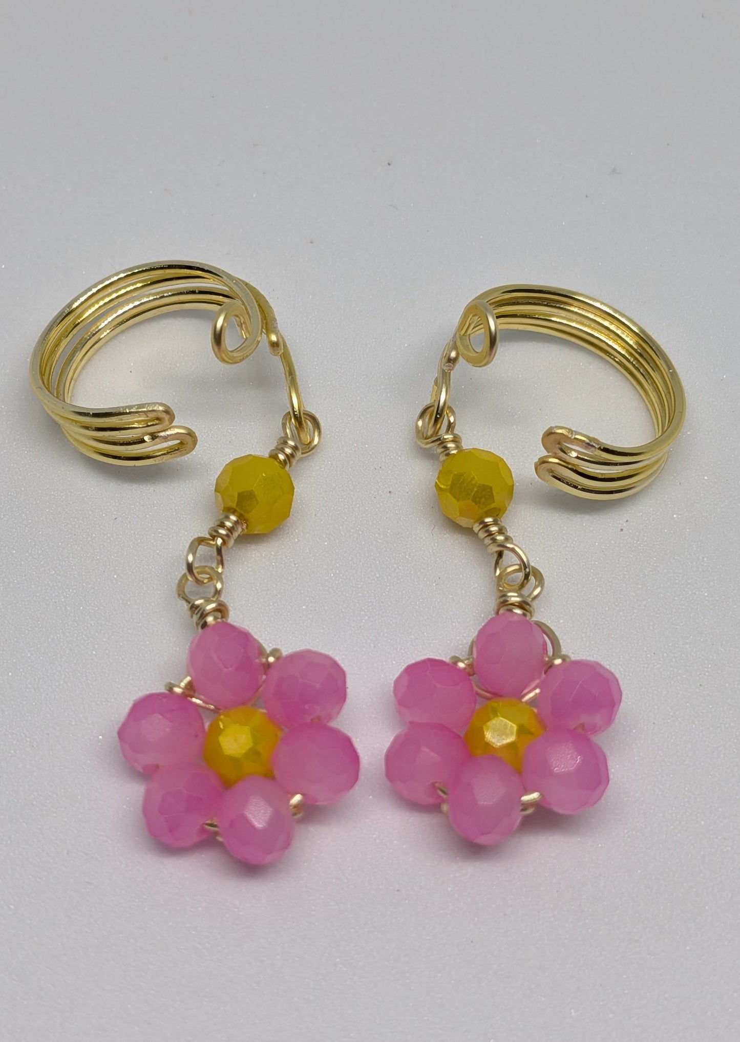 Ein Paar Earcuffs in Hellgold mit Blumenanhänger in sommerlich leuchtendem Pink