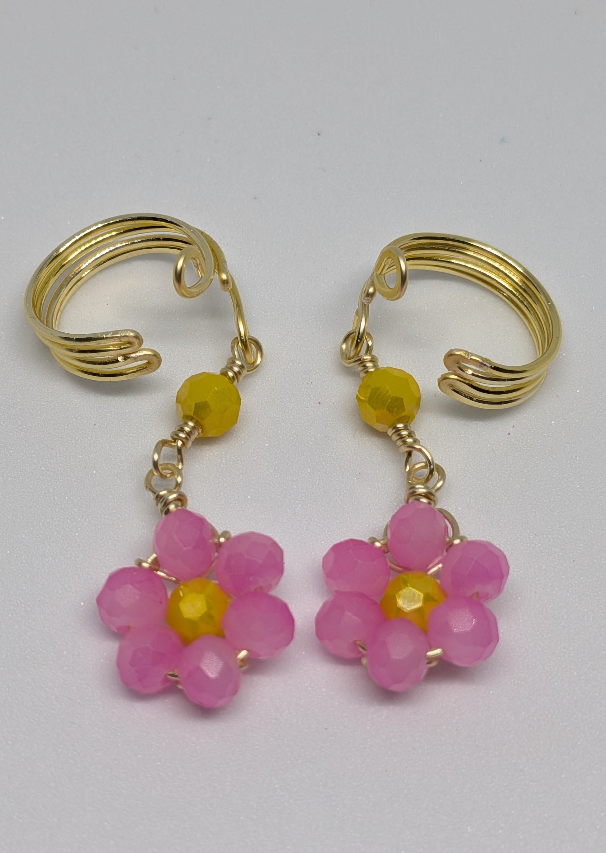 Ein Paar Earcuffs in Hellgold mit Blumenanhänger in sommerlich leuchtendem Pink