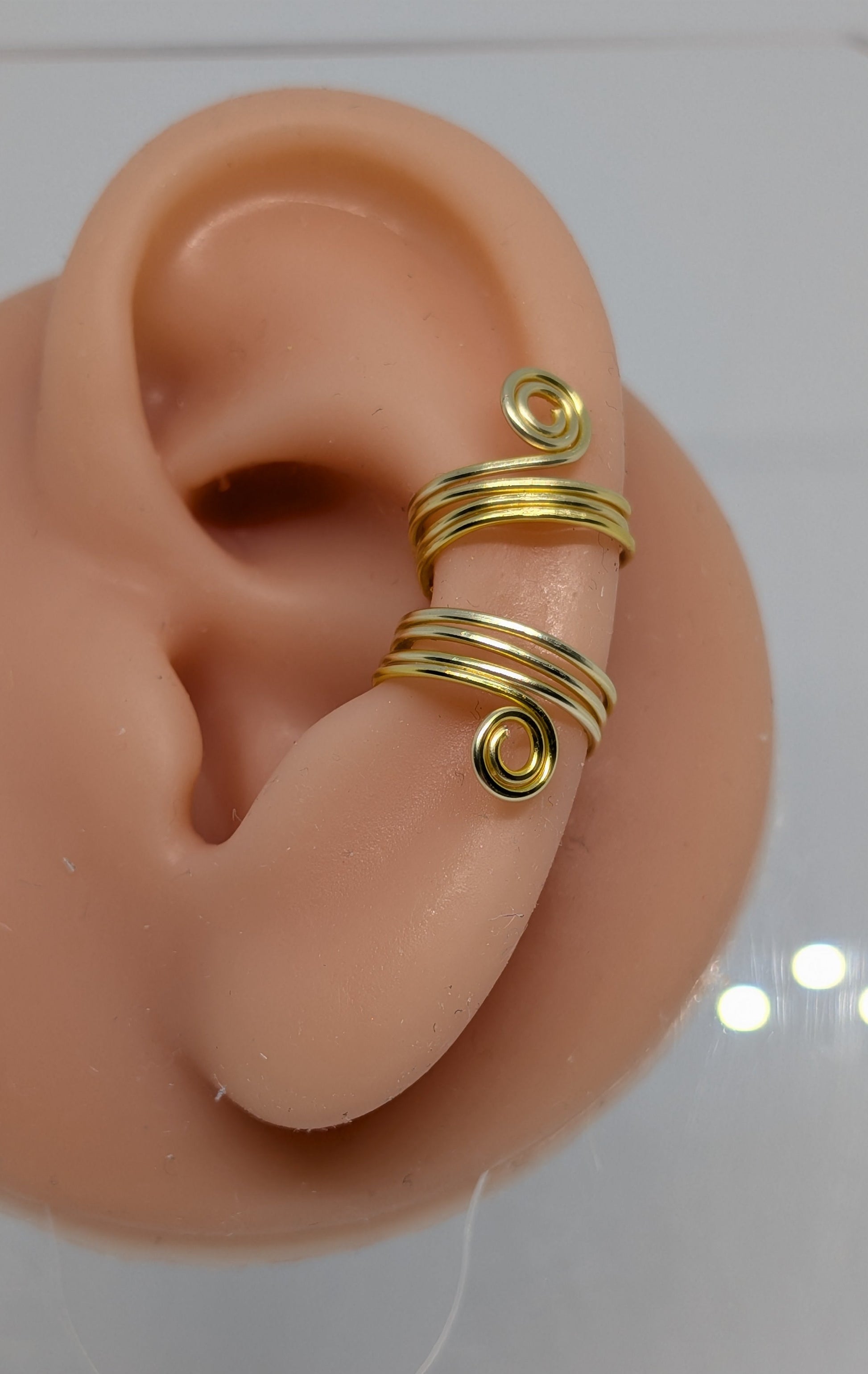Ein Paar Earcuffs in Hellgold mit dekorativen Spiralen