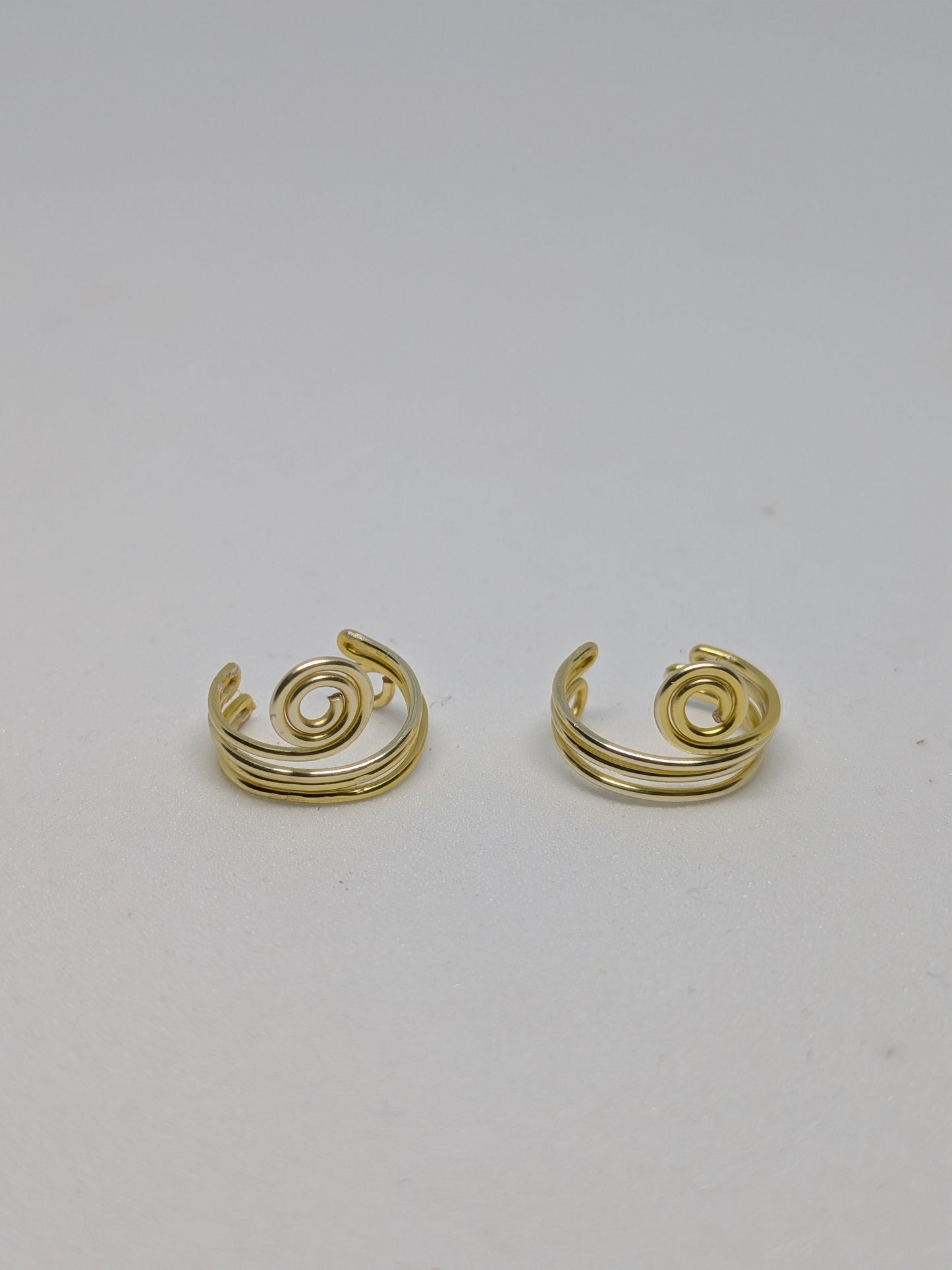 Ein Paar Earcuffs in Hellgold mit dekorativen Spiralen