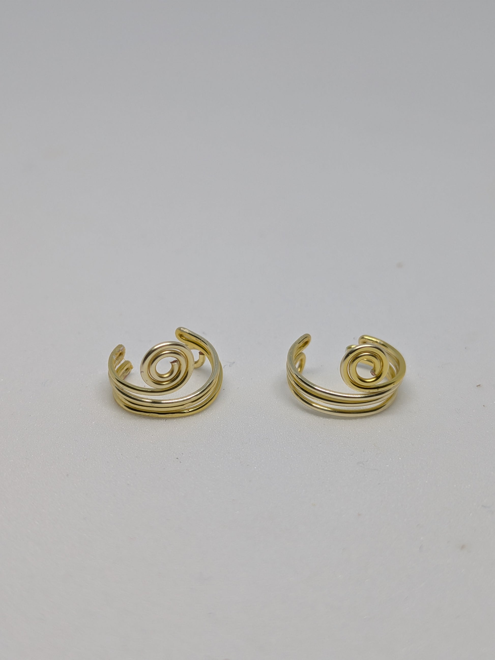 Ein Paar Earcuffs in Hellgold mit dekorativen Spiralen