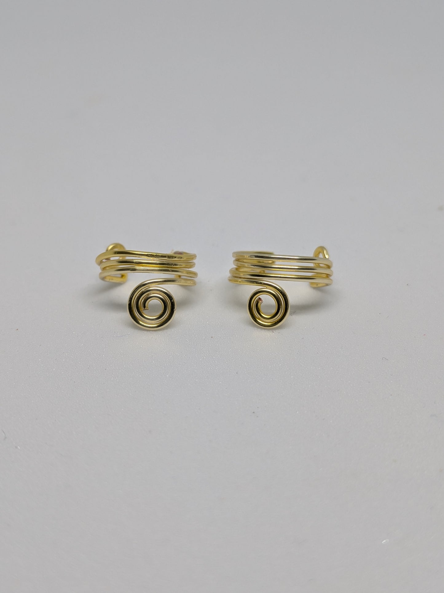 Ein Paar Earcuffs in Hellgold mit dekorativen Spiralen