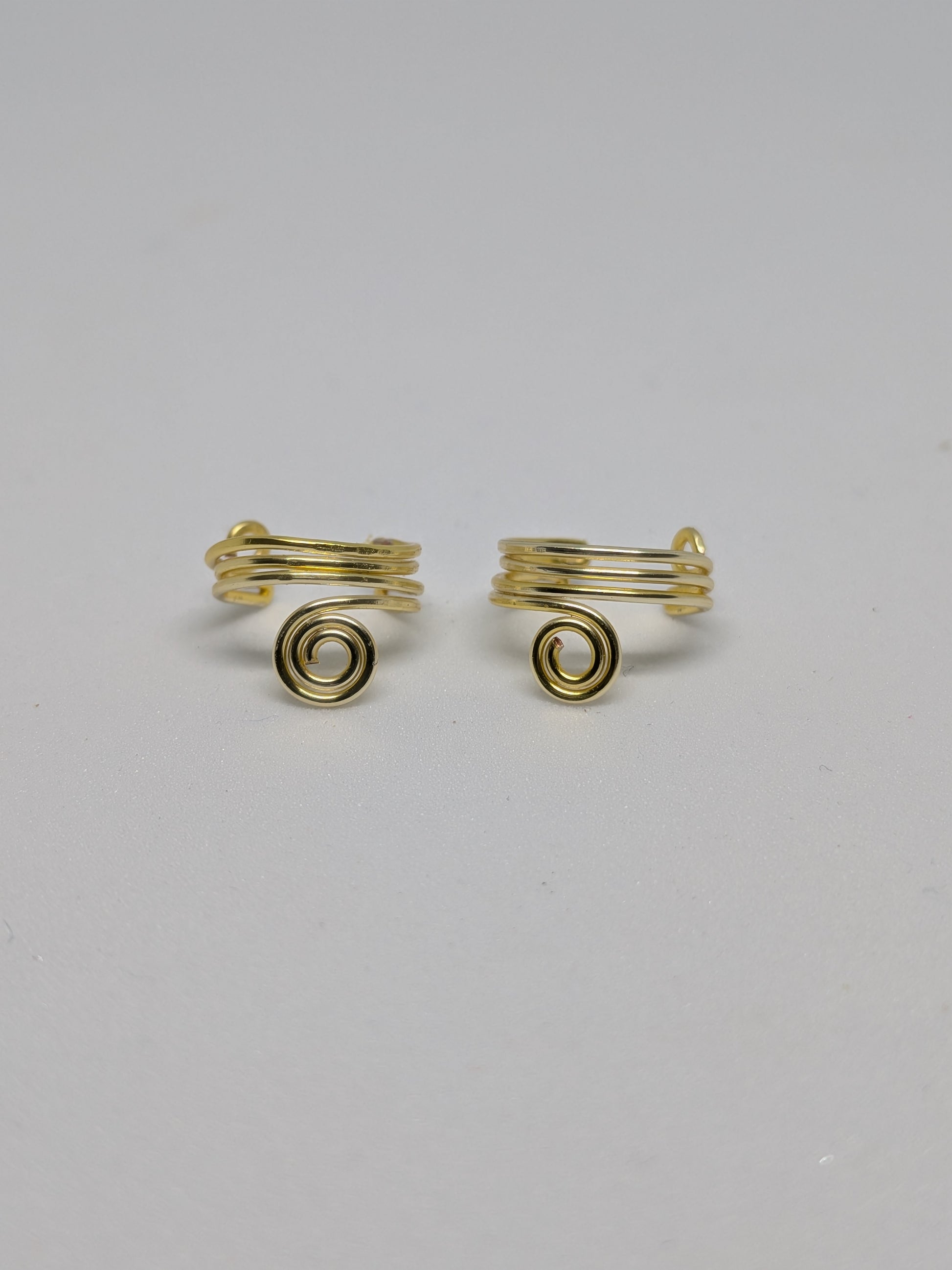 Ein Paar Earcuffs in Hellgold mit dekorativen Spiralen