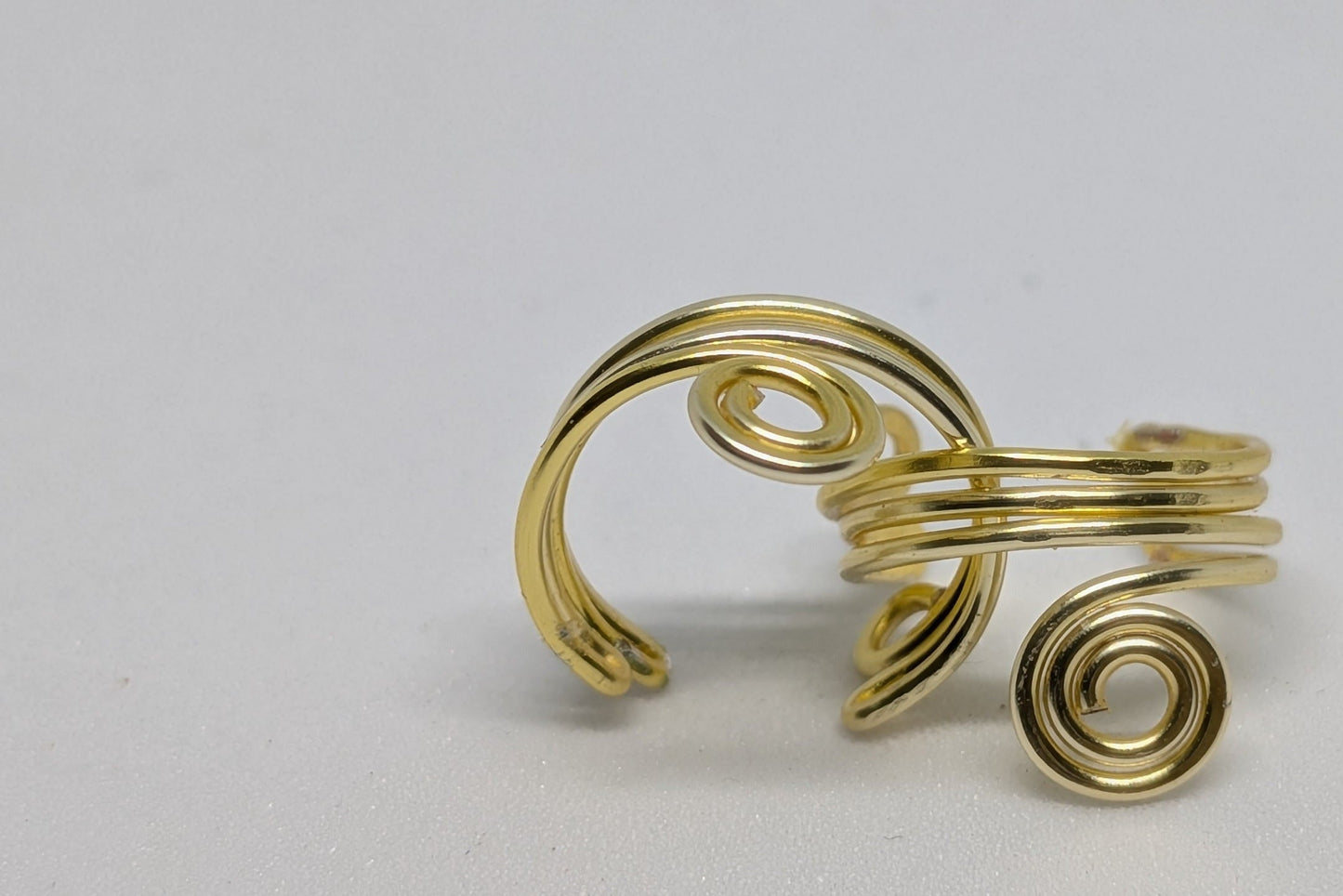 Ein Paar Earcuffs in Hellgold mit dekorativen Spiralen